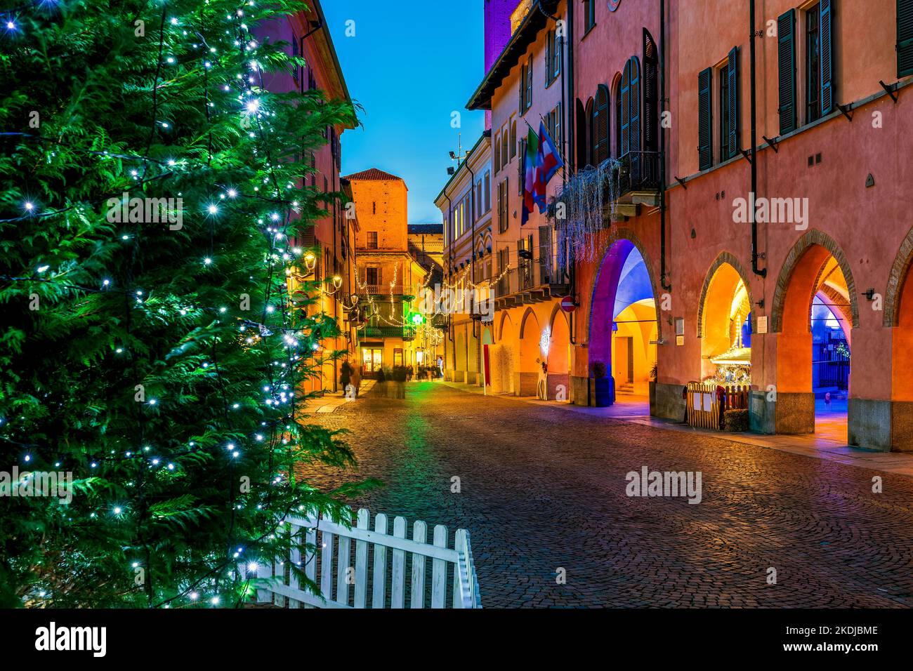 Christmas tree on illuminated and decorated cobblestone street in old town of Alba in Piedmont, Northern Italy. Stock Photo