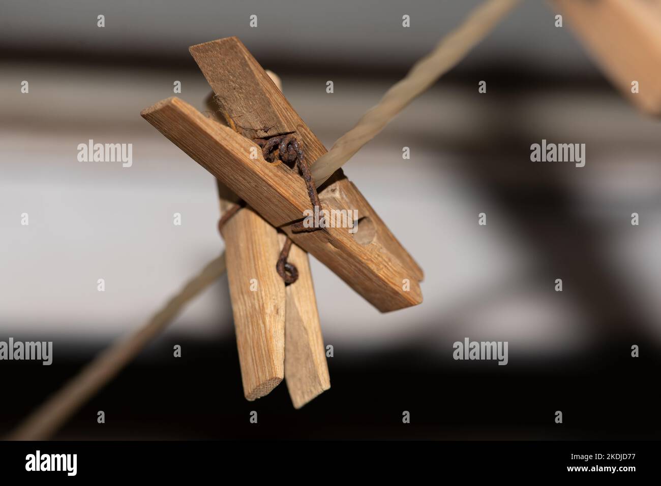 A line of old wooden clothes pegs on a nylon washing line with rusty metal springs make an attractive arrangement against a dark and creamy background Stock Photo