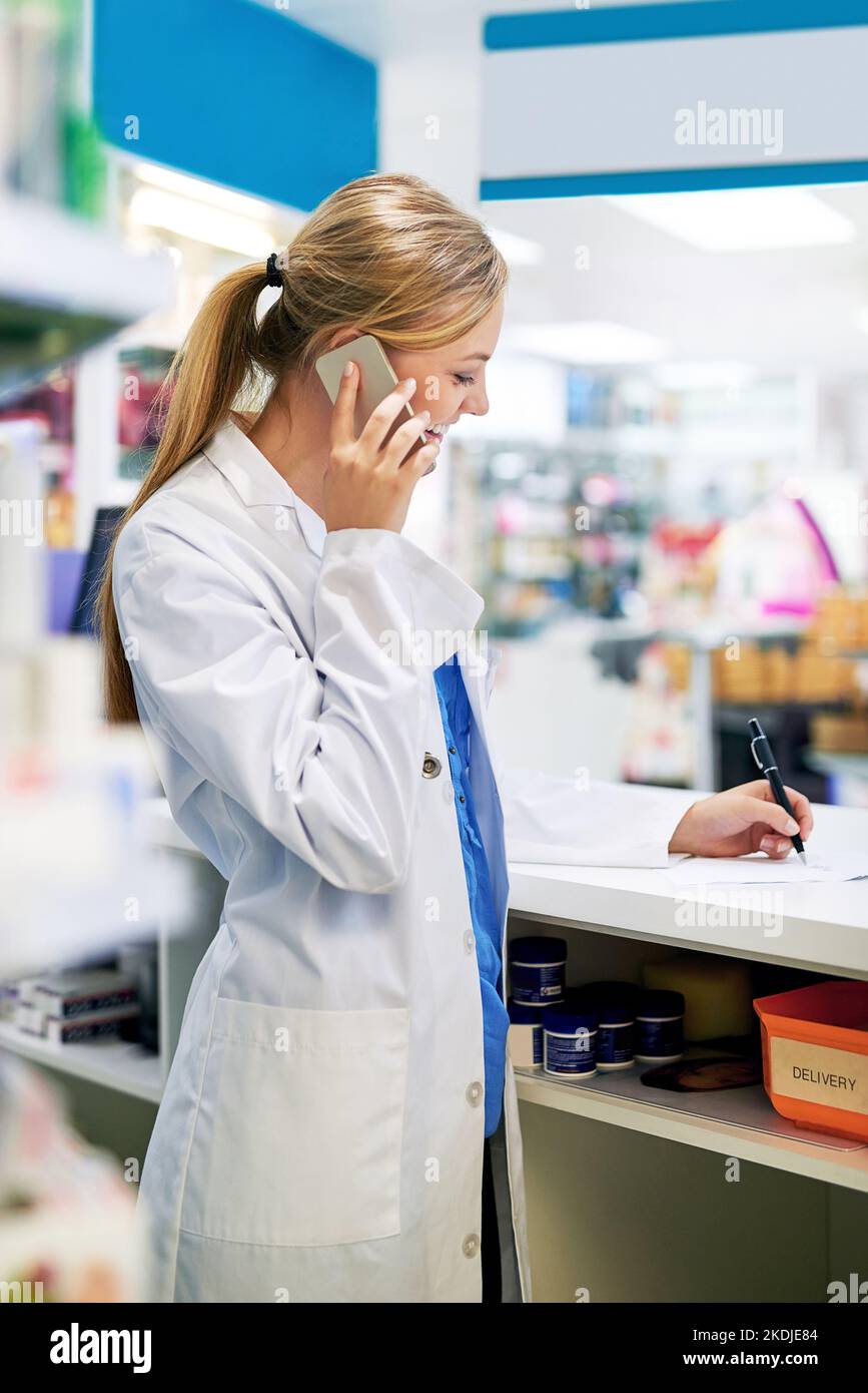 Taking telephonic orders. a young pharmacist talking on a cellphone