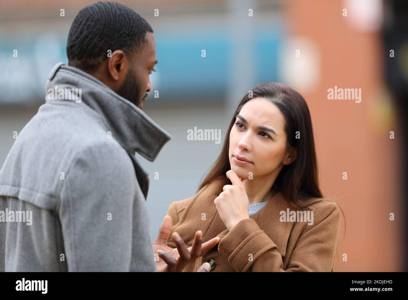 Attentive woman listening a man talking in winter in the street Stock Photo