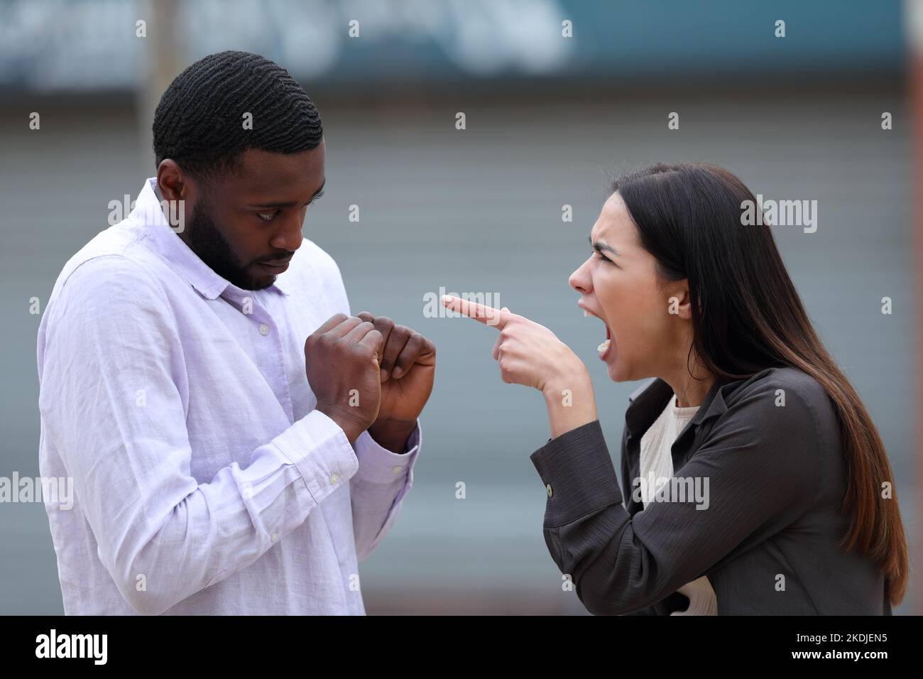 Furious woman scolding to a black man in the street Stock Photo
