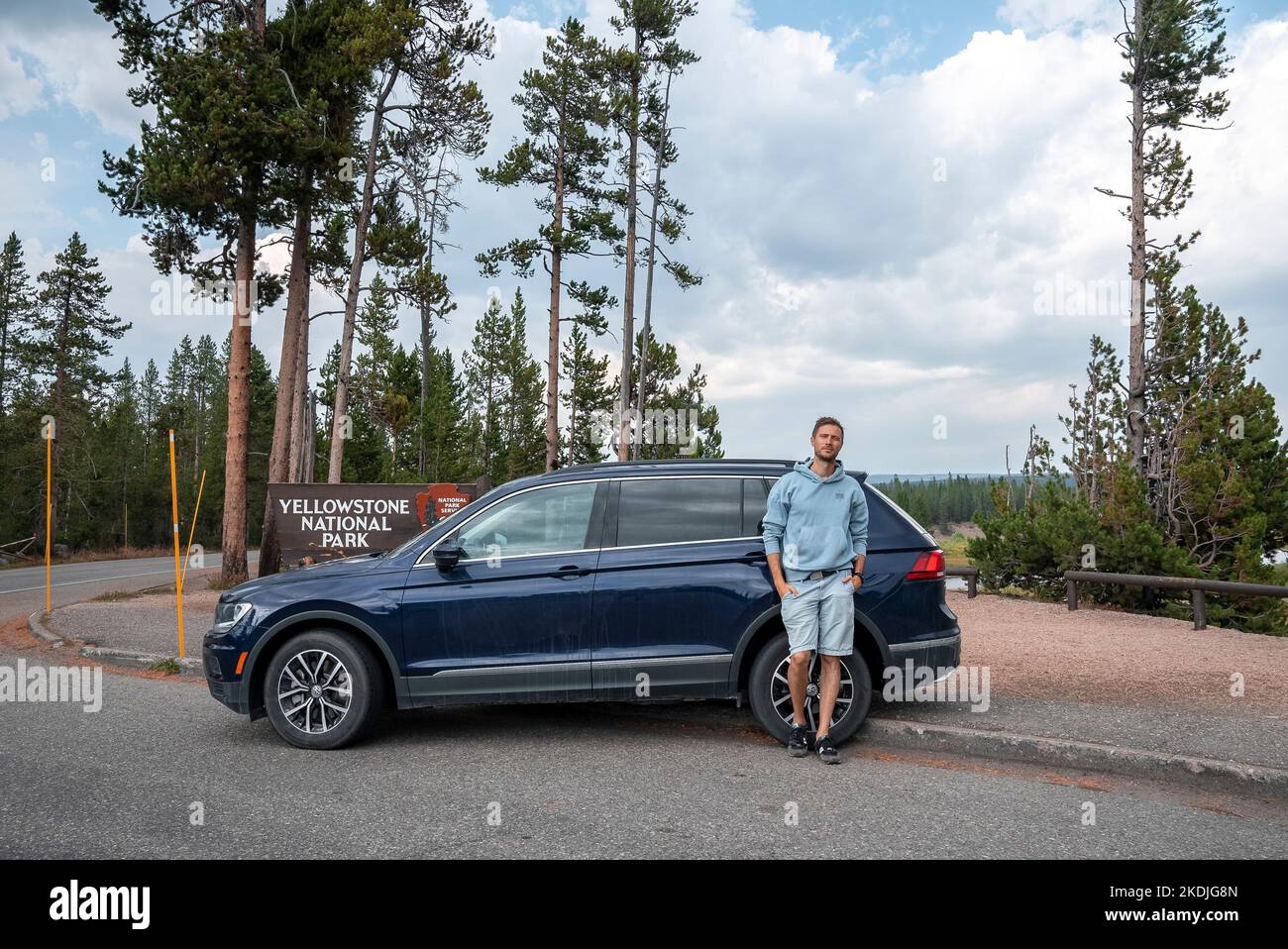 Portrait of tourist is standing by car at entrance of Yellowstone National Park Stock Photo