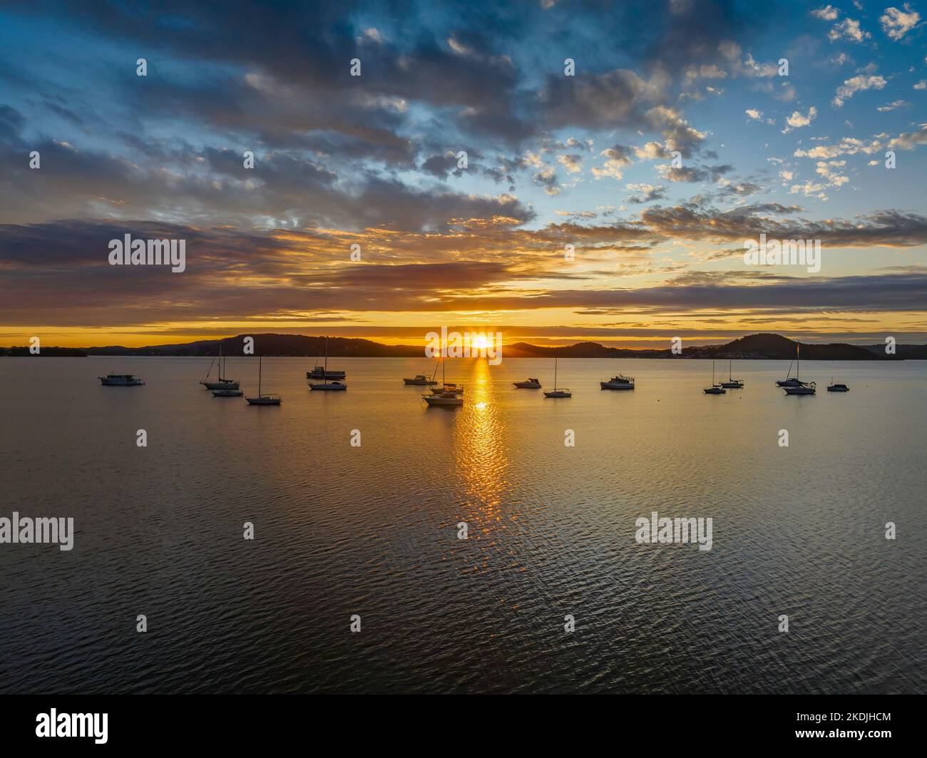 Sun rising over Brisbane Water with clouds and boats at Koolewong and Tascott on the Central Coast, NSW, Australia. Stock Photo