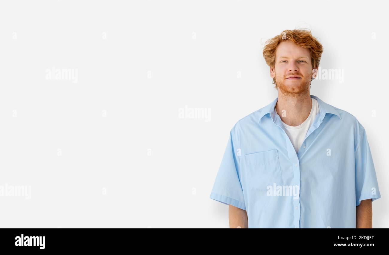 Portrait of caucasian redhead young man in blue shirt standing on a white background with copy space Stock Photo