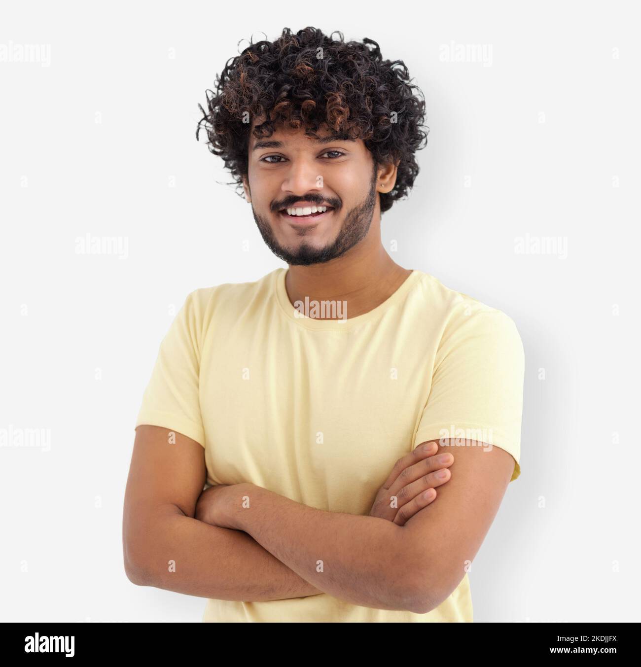 Portrait of happy Asian man guy with curly hair and white teeth in a yellow t-shirt standing on white background Stock Photo