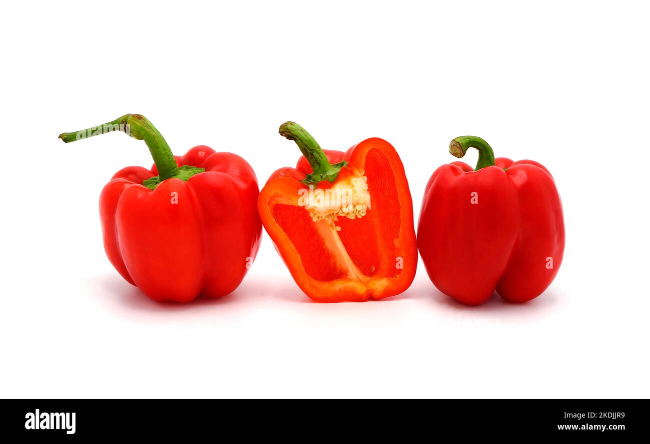 Two red ripe sweet peppers and one pepper in a cut on a light