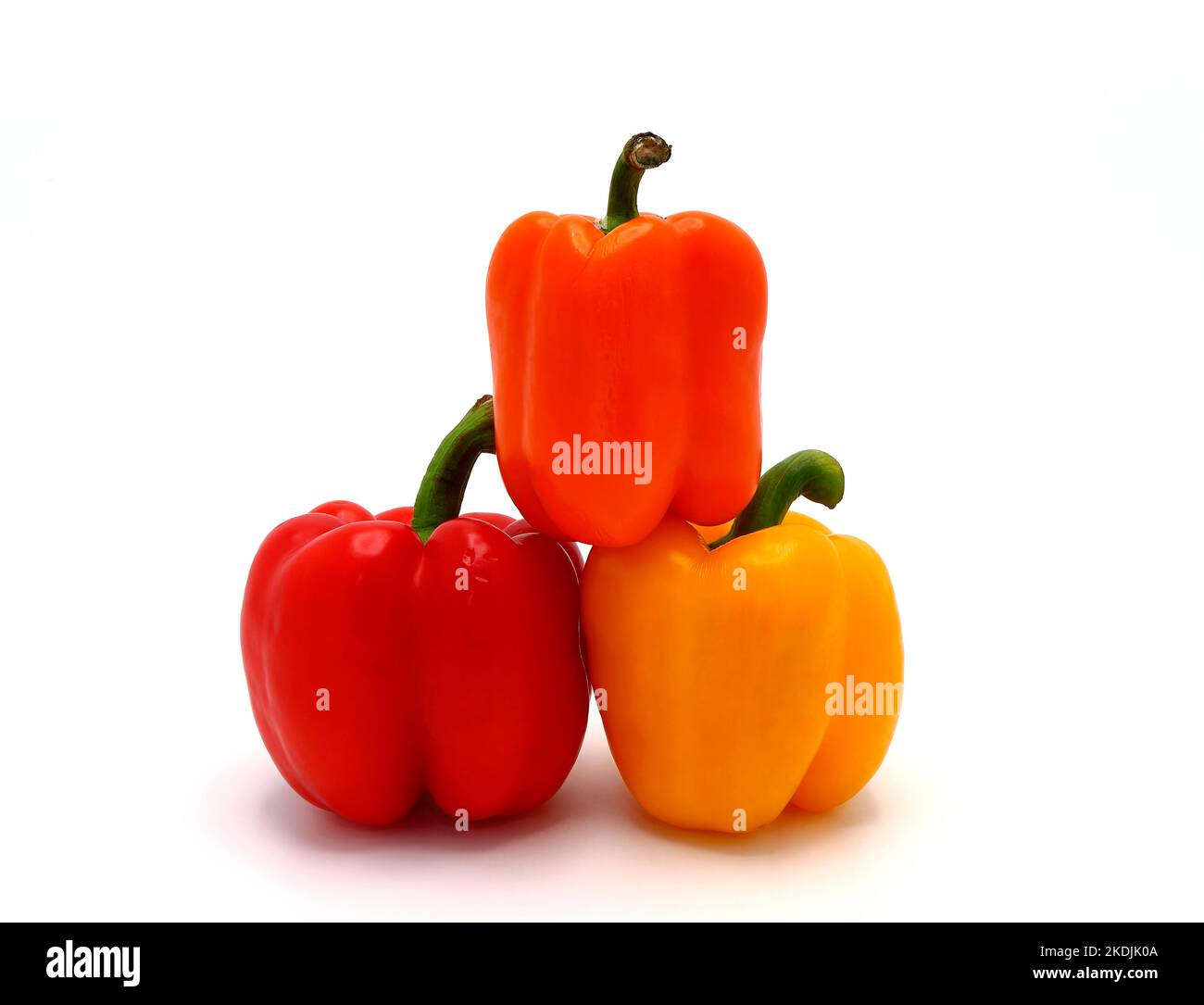 Three sweet peppers of yellow, red and orange color on a light