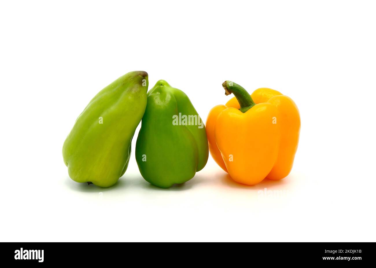 Three sweet peppers of yellow and green color on a light background