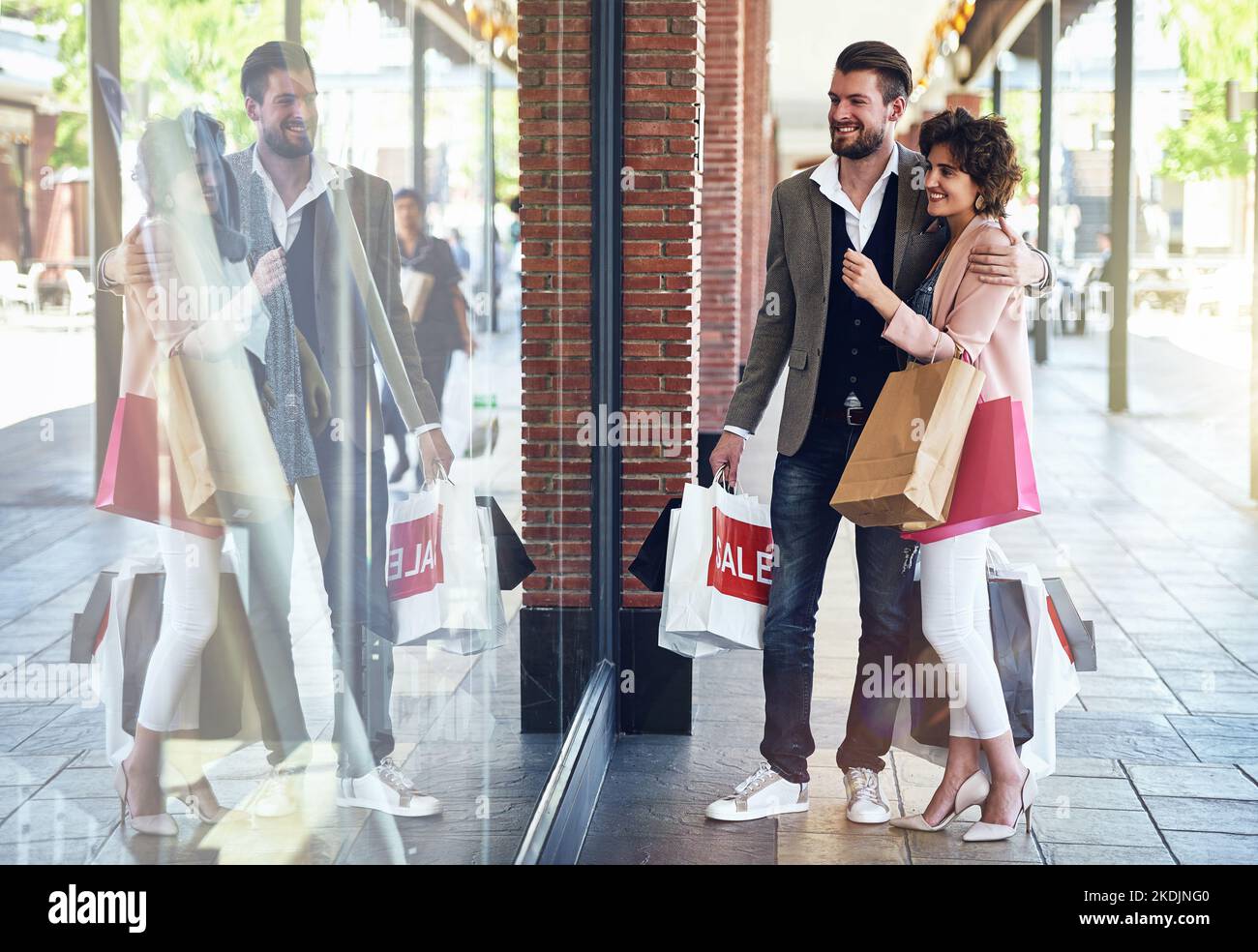 Lets go check if they have my size in that. a couple looking at something that on display in a shops window. Stock Photo