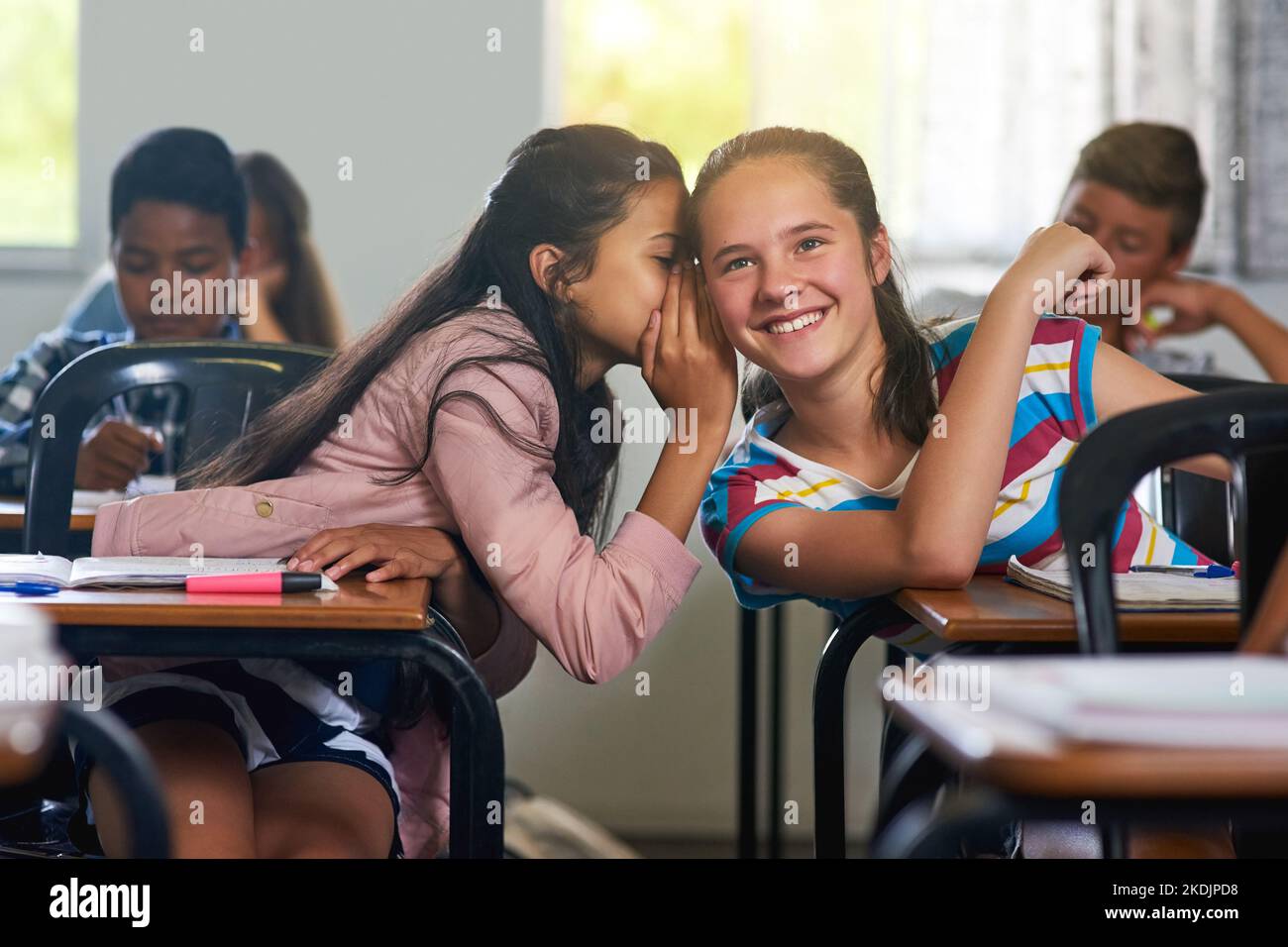 Guess what I heard. a young schoolgirl whispering a secret to her friend in class. Stock Photo