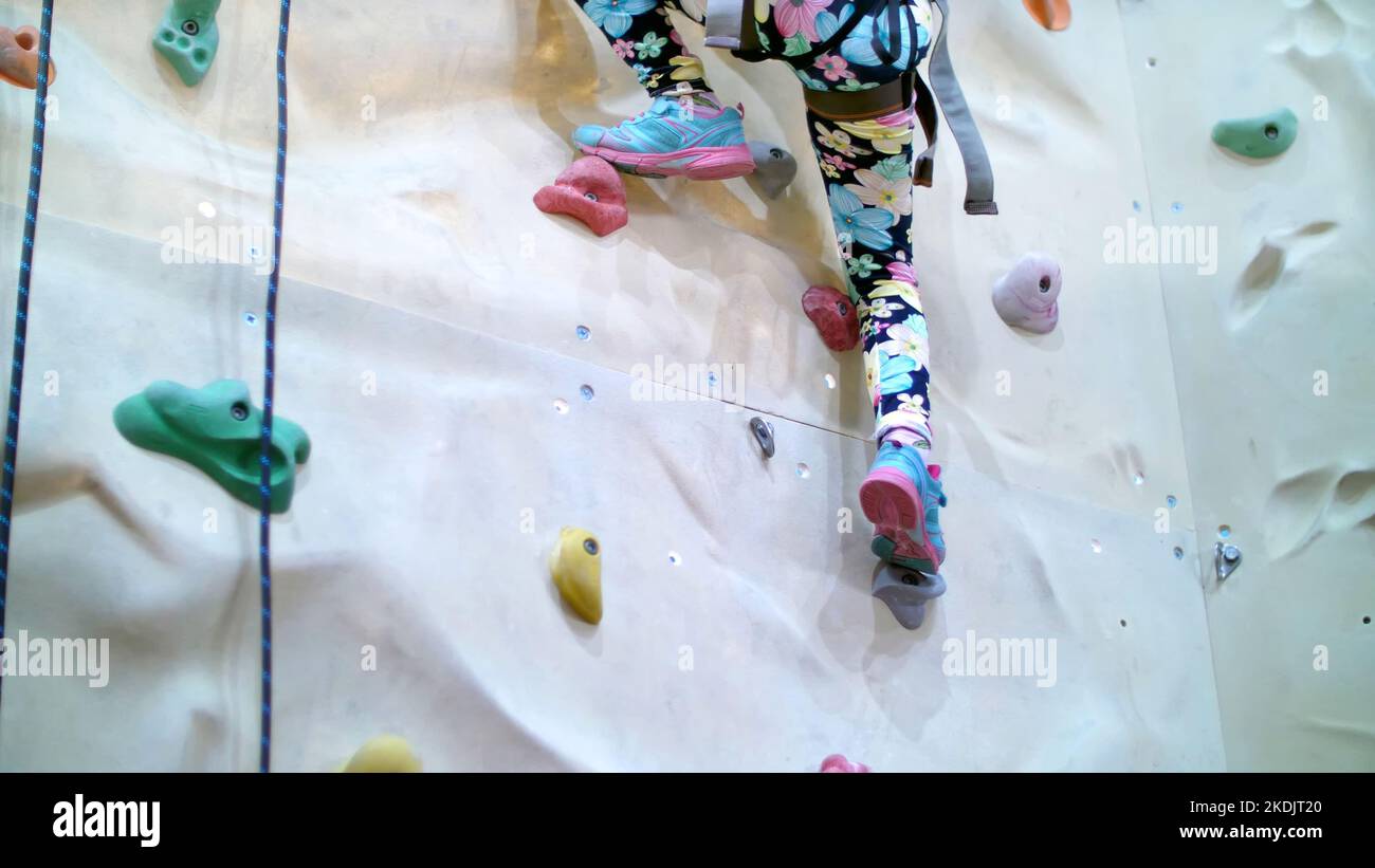 child climbs on a special wall for mountaineering. the girl of seven years in safety equipment is engaged in rock climbing on a special training vertical wall,. High quality photo Stock Photo