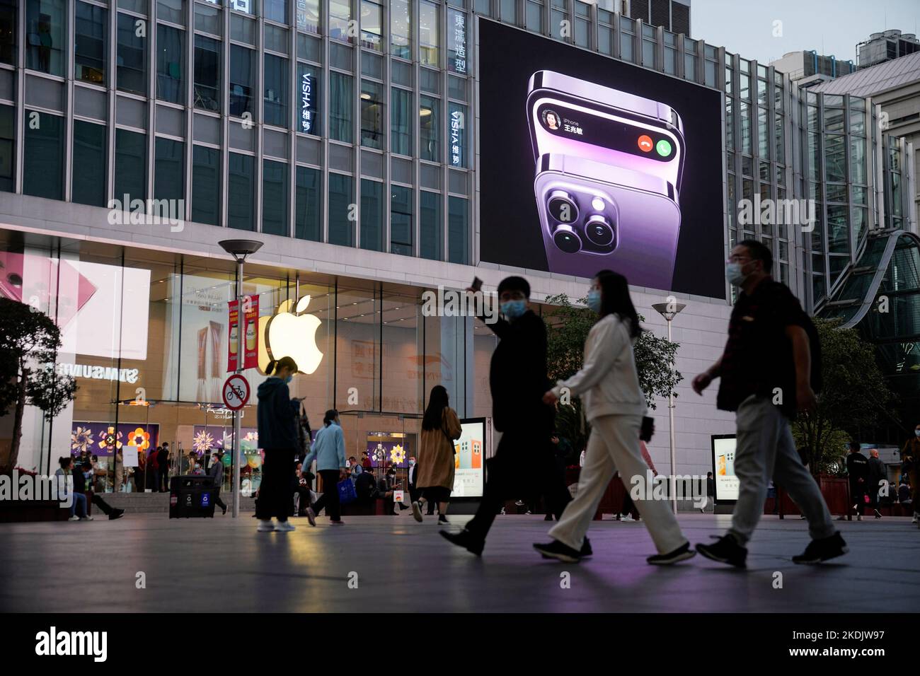 People walk near a display advertising the Apple iPhone 14 outside its store, following the coronavirus disease (COVID-19) outbreak in Shanghai, China, November 7, 2022. REUTERS/Aly Song Stock Photo