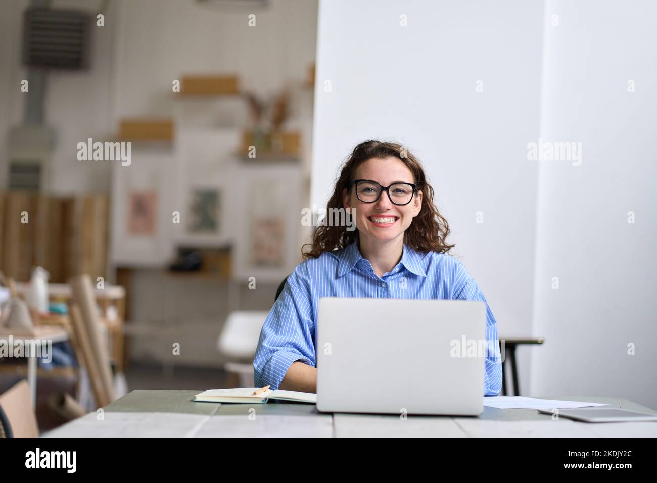 Young happy business woman company employee sitting at desk working on laptop. Stock Photo