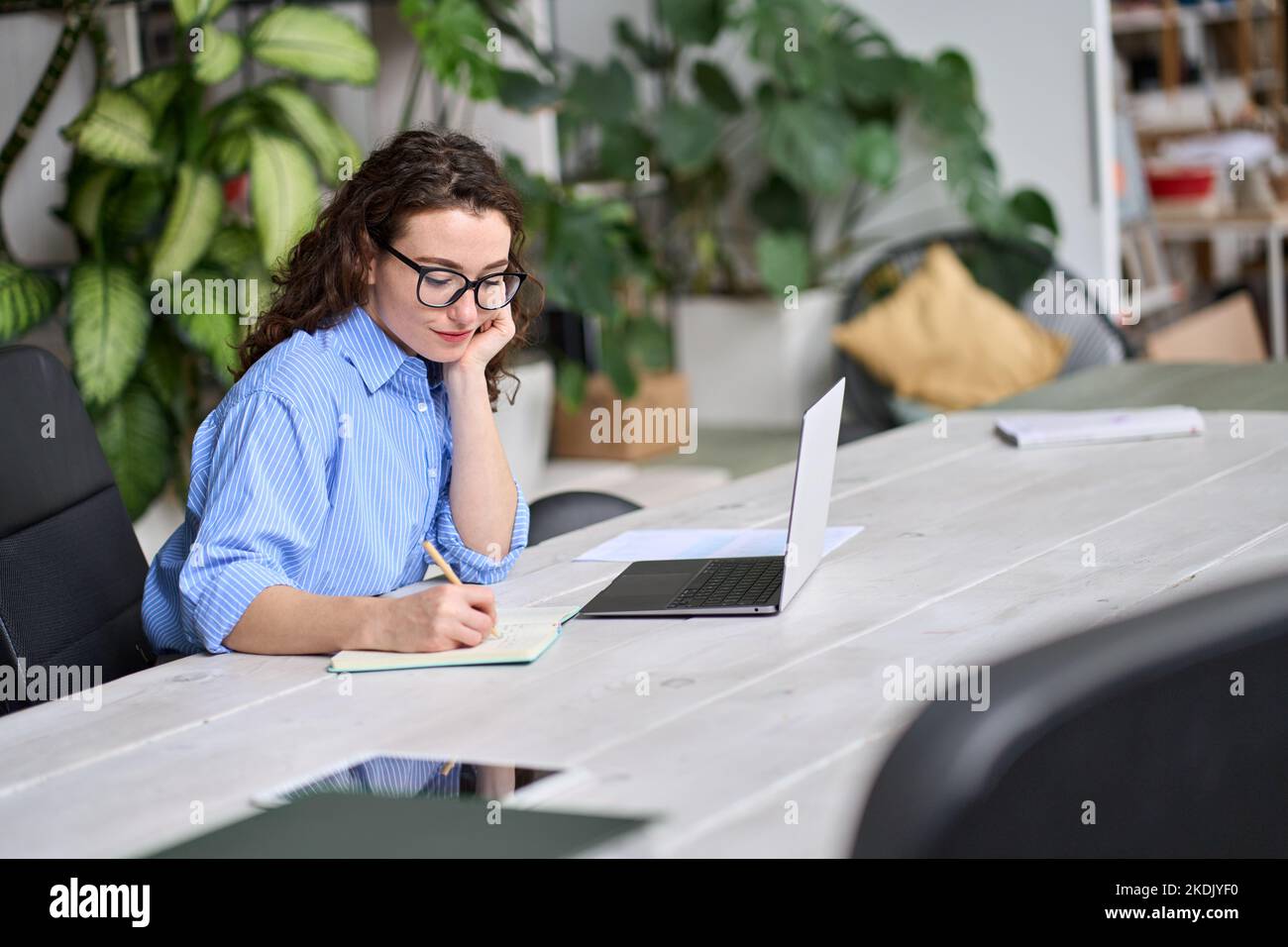 Young business woman or student using laptop working or learning taking notes. Stock Photo