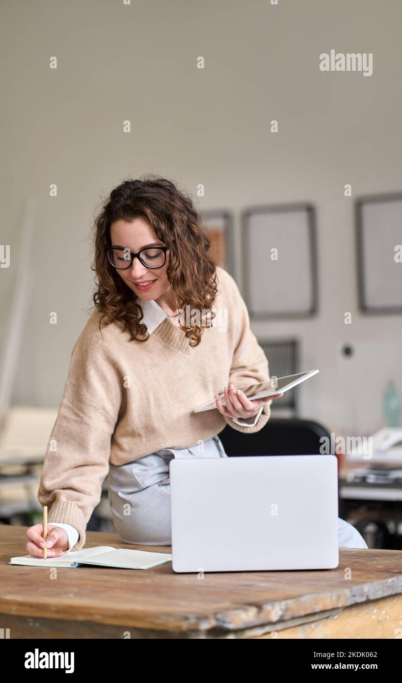 Young smiling business woman working in office using digital tablet. Vertical Stock Photo