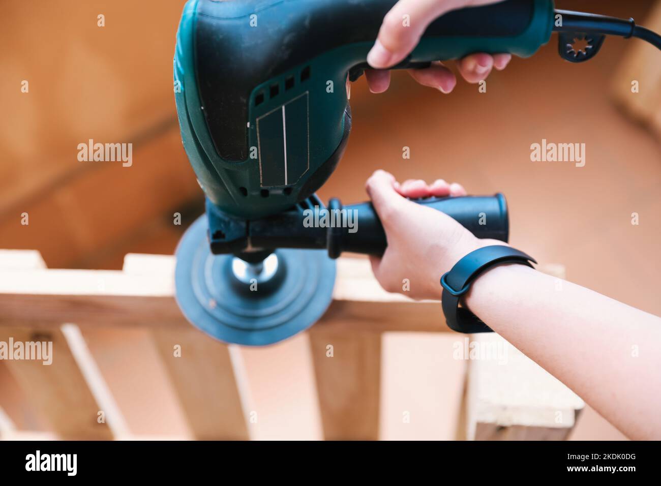 Closeup of two hands of an unrecognizable woman sanding a pallet with