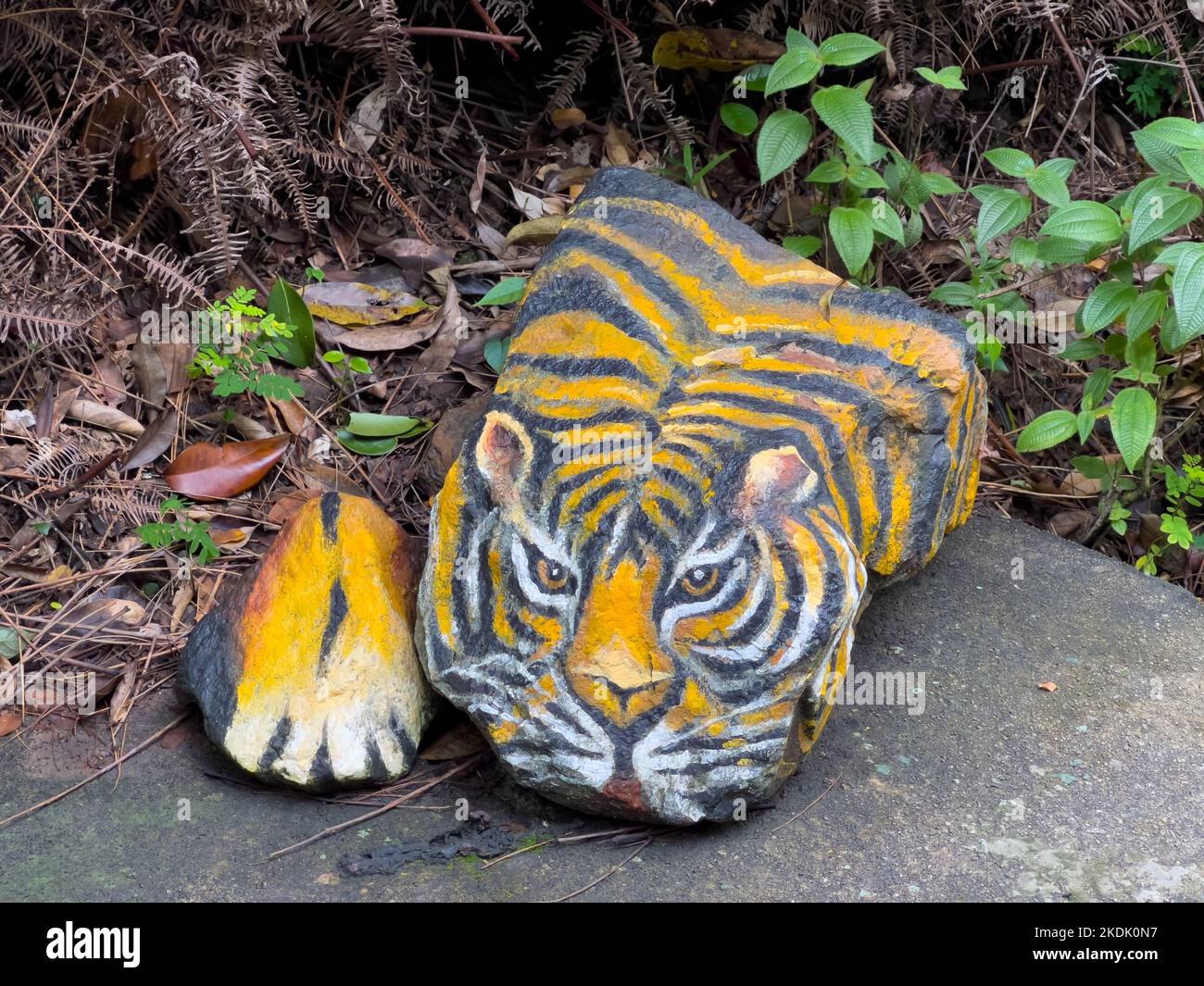 Painted tiger on a large rock at an outdoor environment for the visitors to check out. Stock Photo