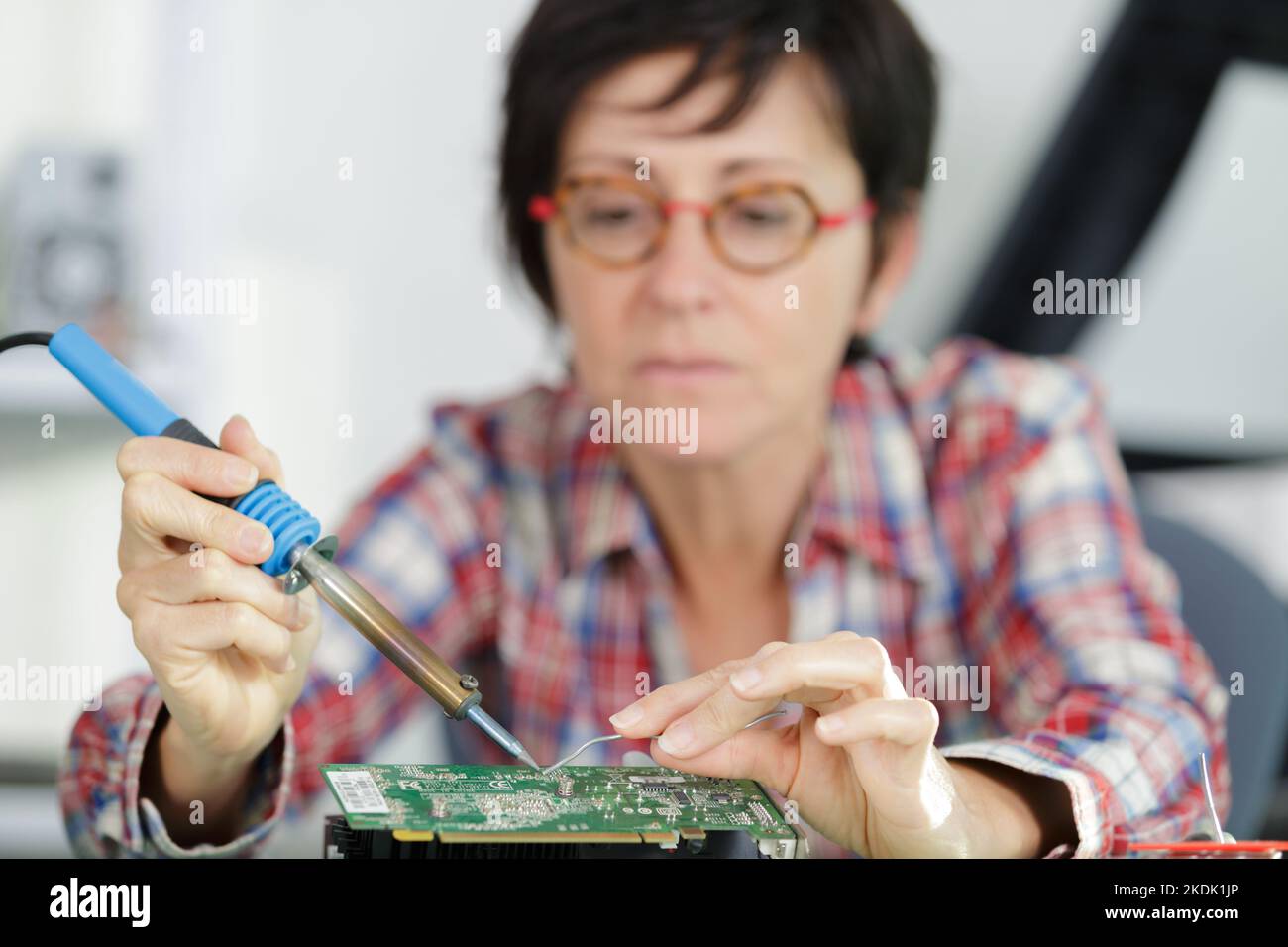 young female tech or engineer repairs electronic equipment Stock Photo