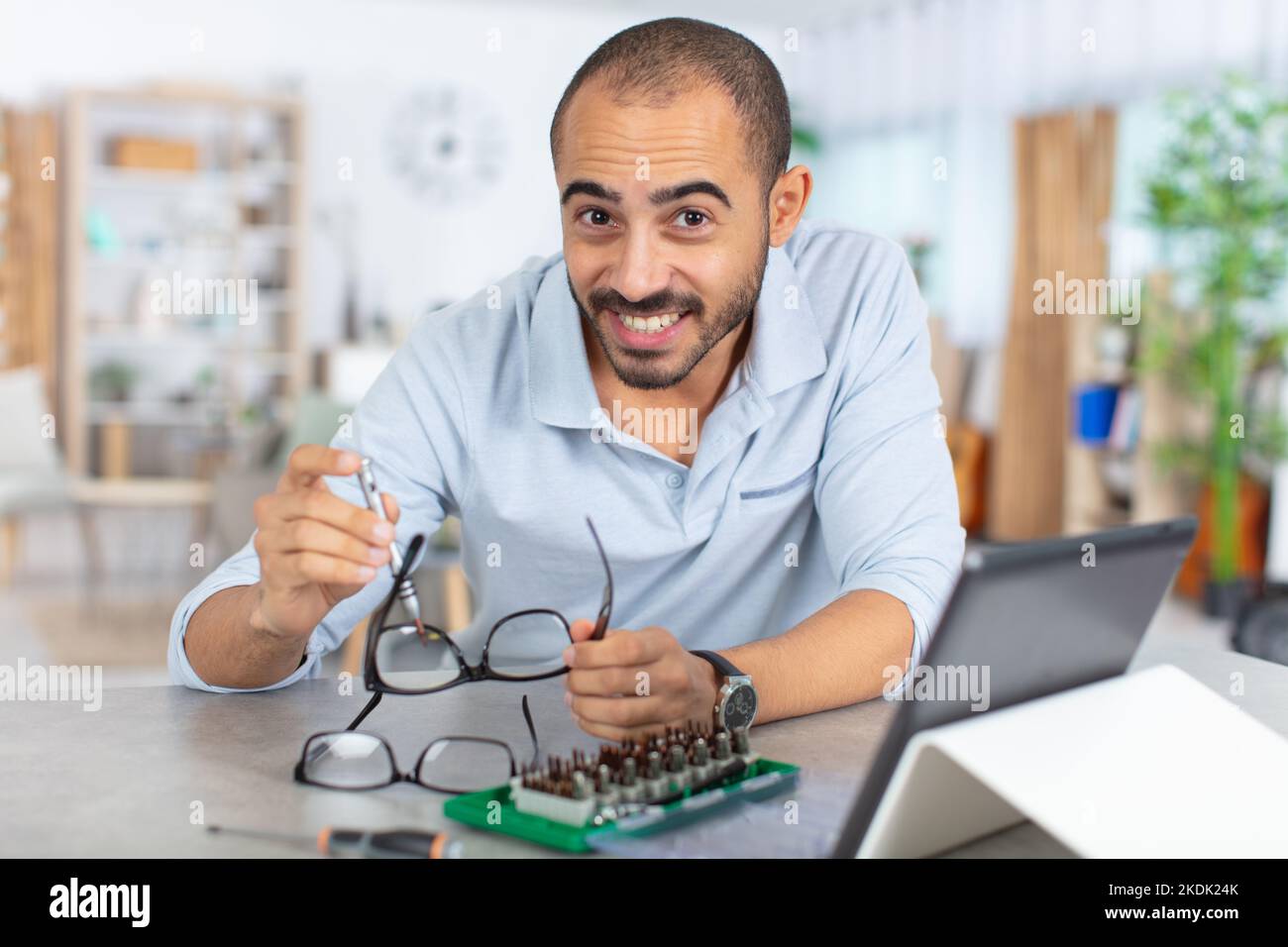 man follows online instructions on tablet to repairs eyeglasses Stock Photo