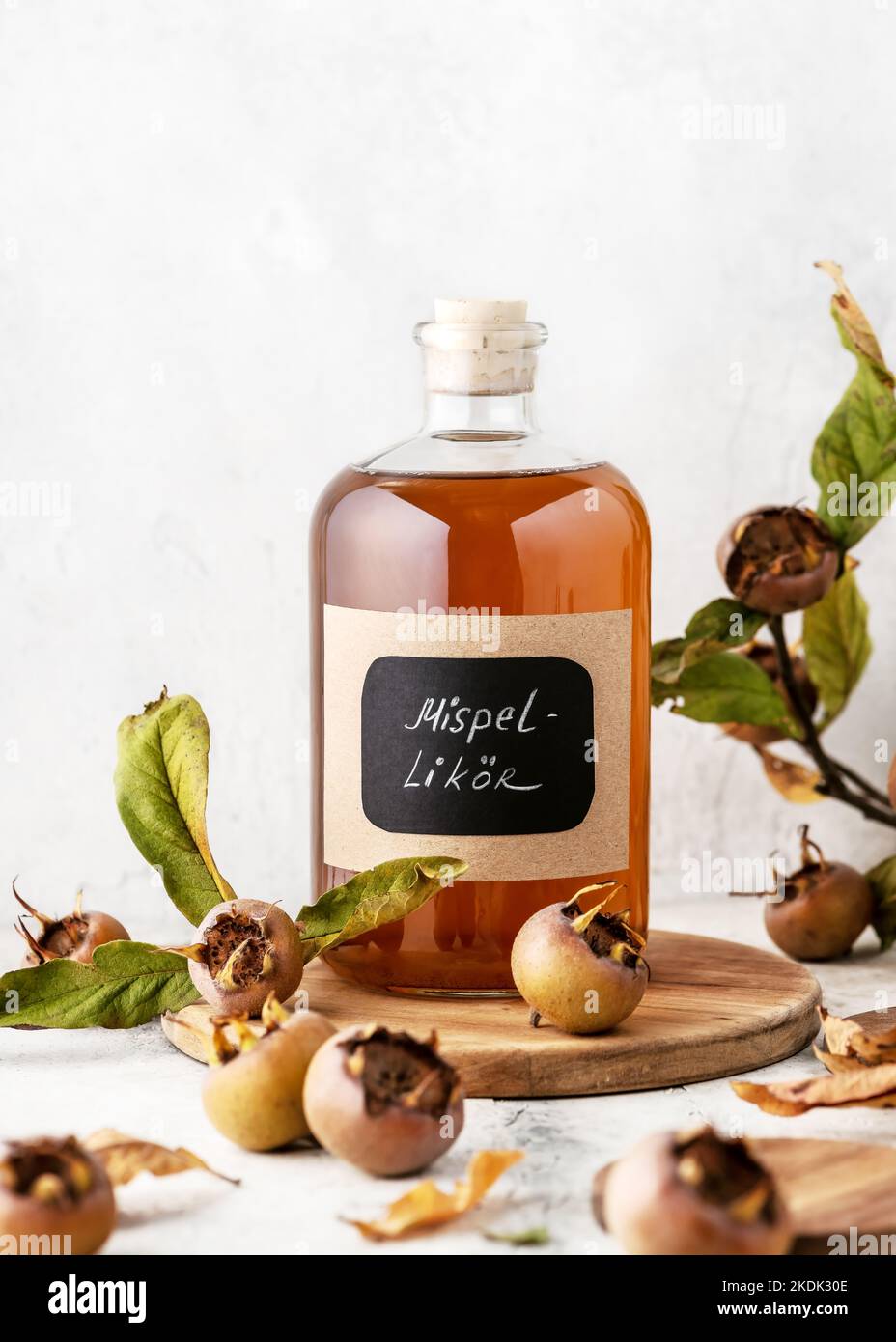 Glass bottle of aromatic homemade medlar fruit liquor with German text 'Mispel likör'on it. Alcohol drink concept. (Mespilus germanica) Stock Photo