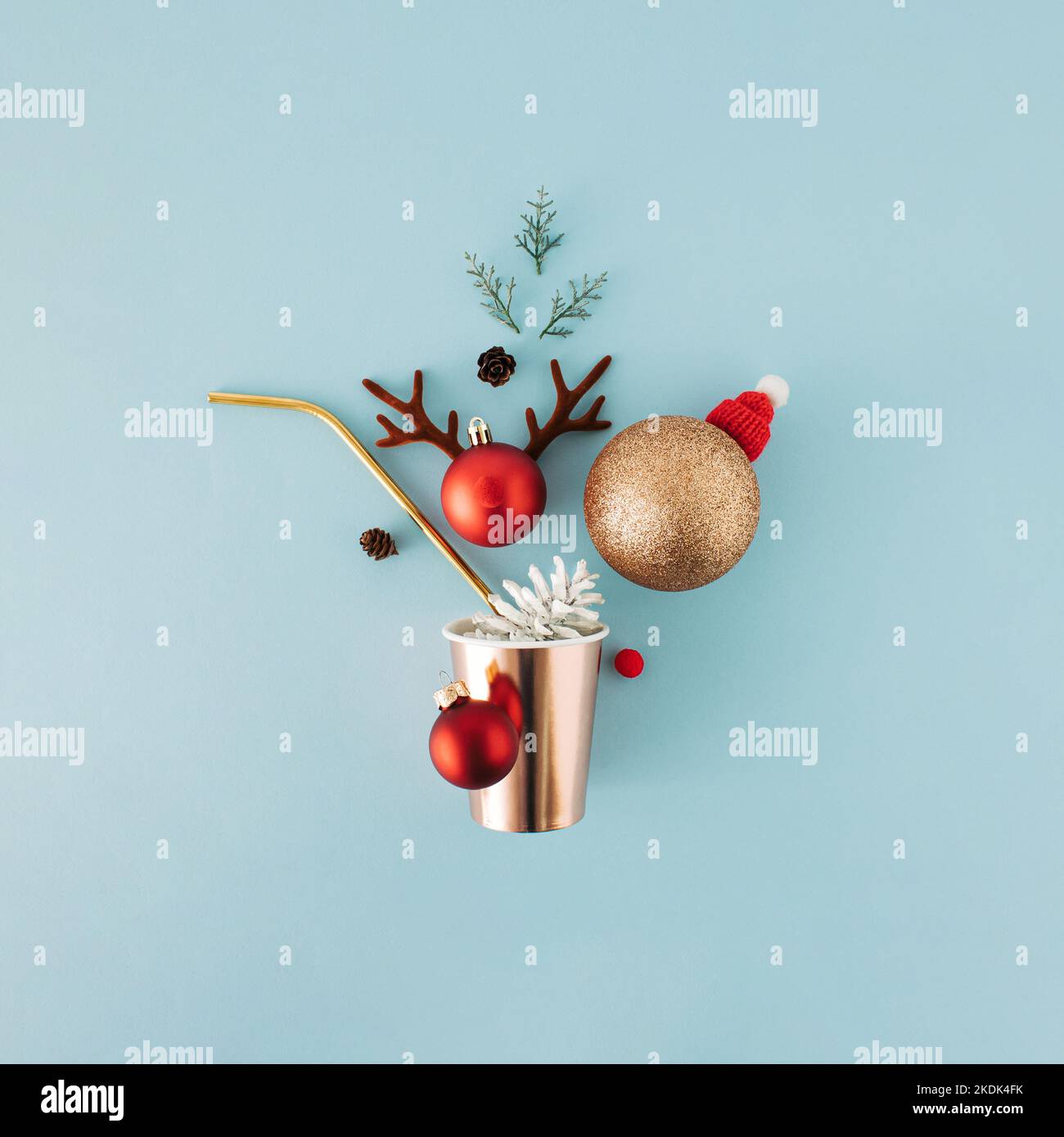 Christmas greeting concept with paper drinking glass, straw and ornaments on blue background. Stock Photo