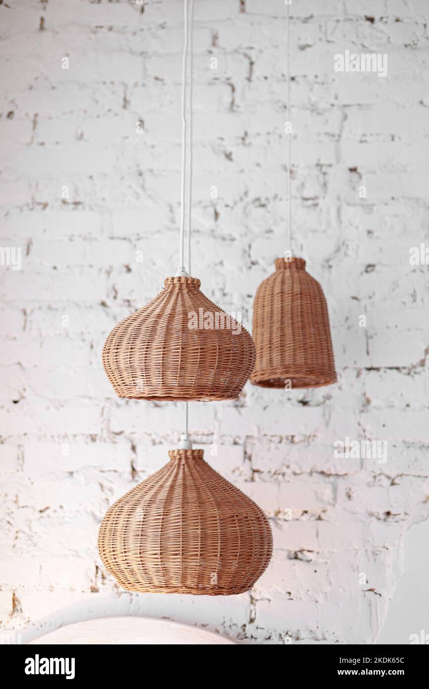 three rattan chandeliers different forms on white brick wall background ...