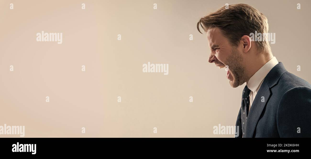 Yelling and screaming. Man face portrait, banner with copy space. Business man in suit, isolated studio background, banner poster. Angry man yell grey Stock Photo