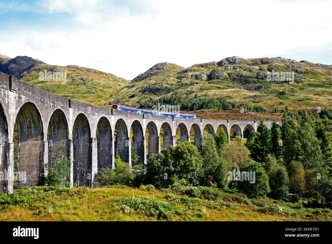 A view of the Glenfinnan Viaduct with a diesel train crossing in autumn