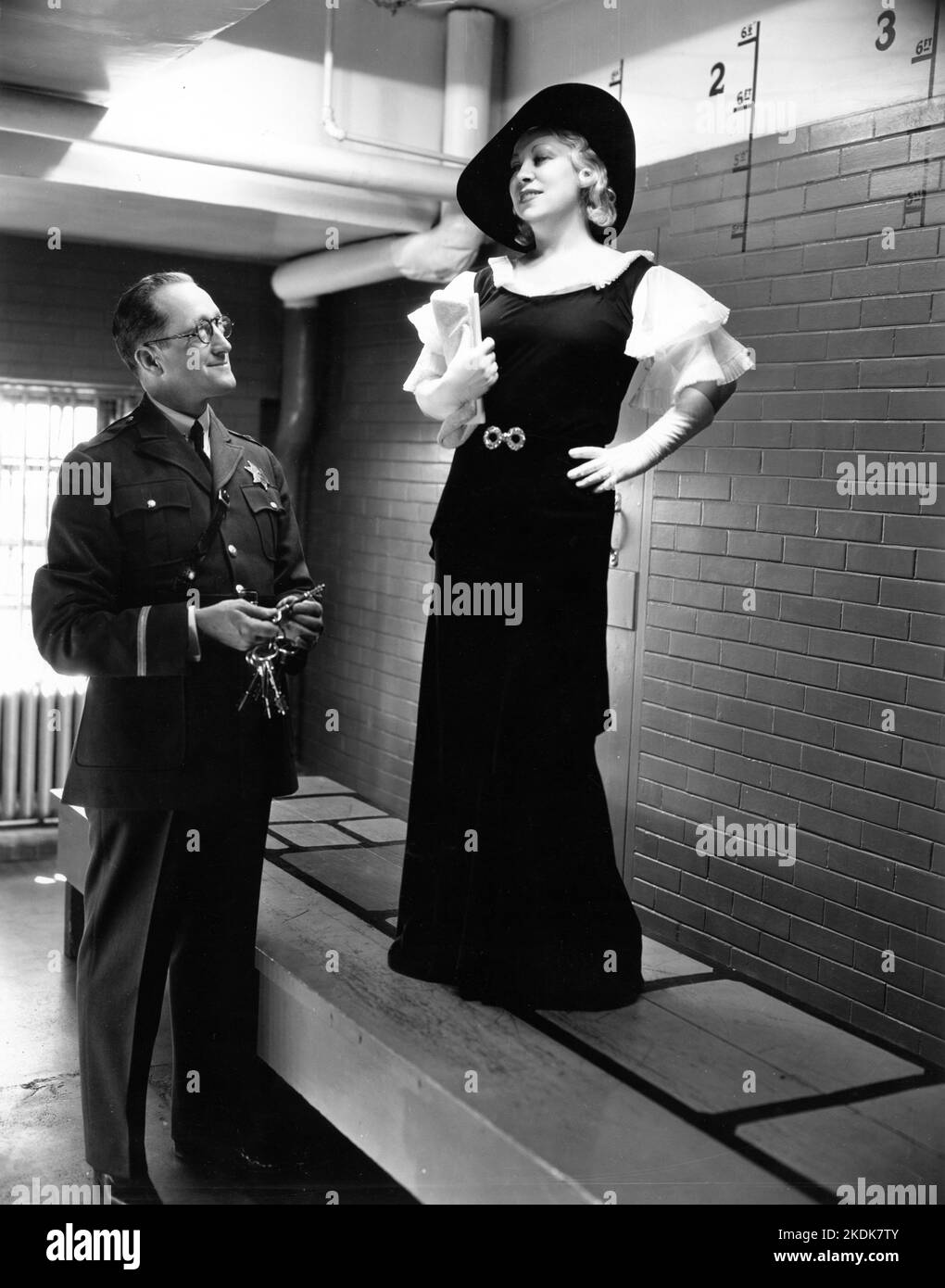 MAE WEST in 1933 with Chief Jailer CLEM PEOPLES inside the ''show-up'' box at Los Angeles County Jail publicity for Paramount Pictures Stock Photo