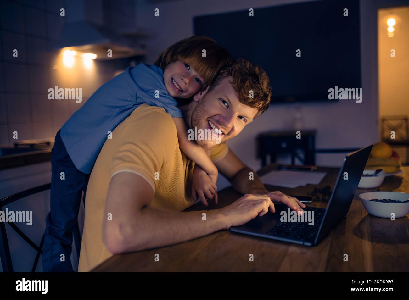 Ginger man nad his cute son watching something on internet in the evening Stock Photo