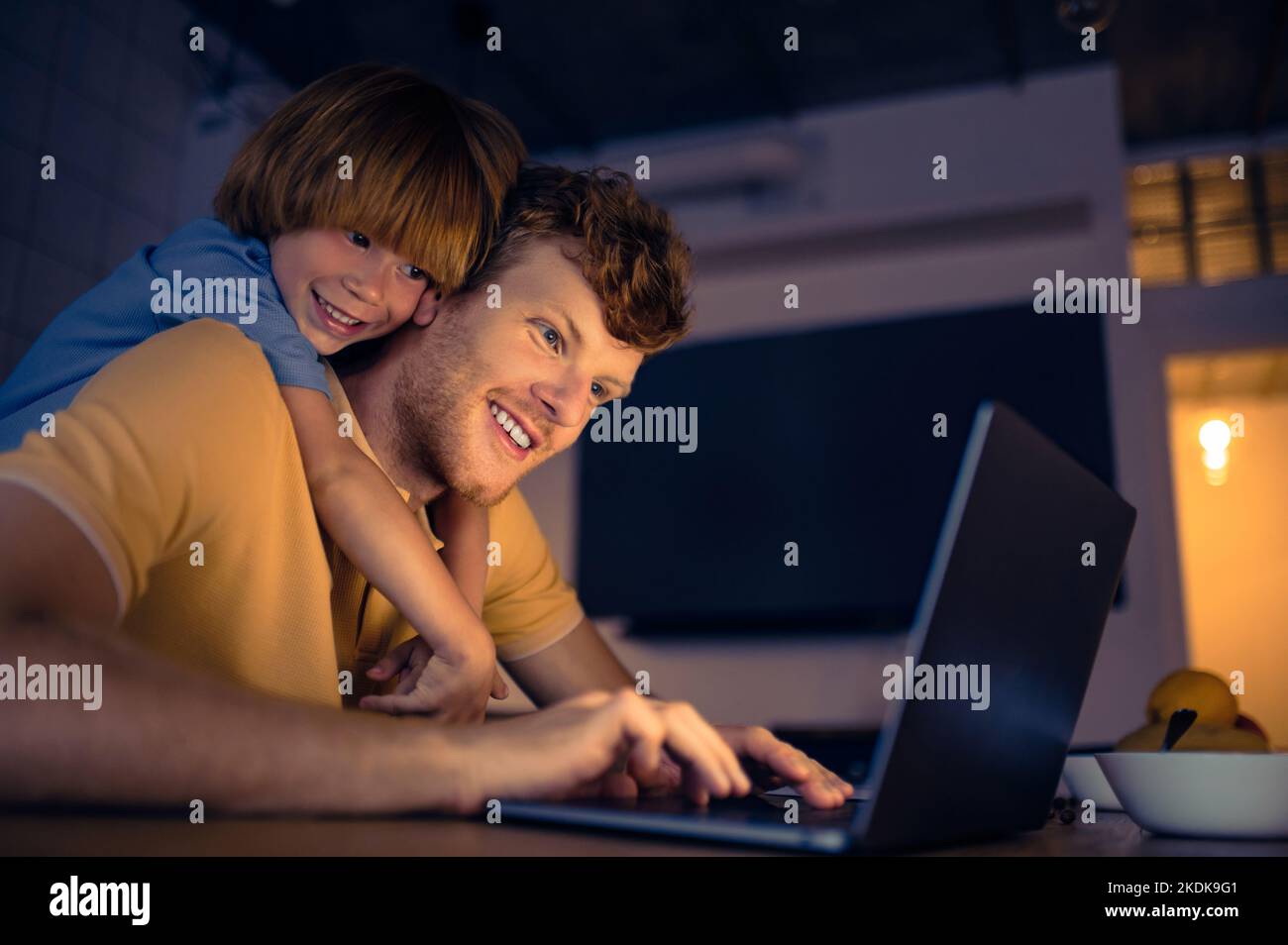 Ginger man nad his cute son watching something on internet in the evening Stock Photo