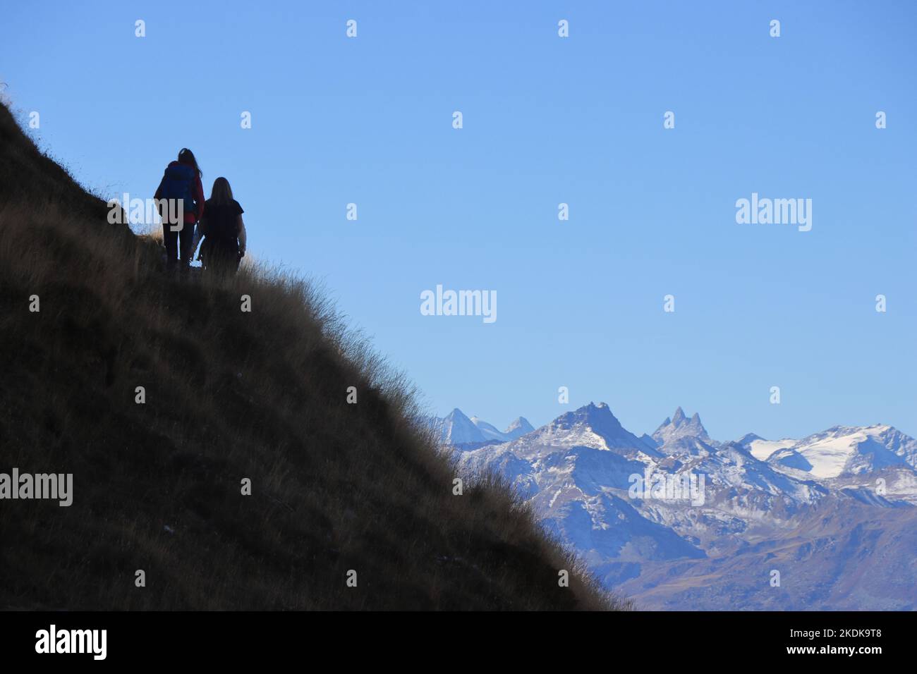 Panoramic hiking trail from Torrent/Rinderhütte to Wysse See. Two hikers at the horizon, mountains in the background. Stock Photo