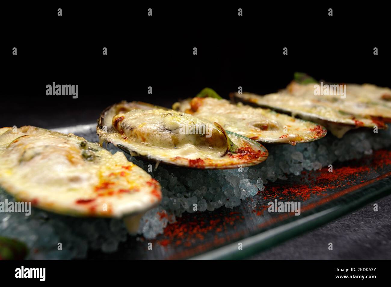 New Zealand mussels baked with cheese and spices, on a dark background Stock Photo