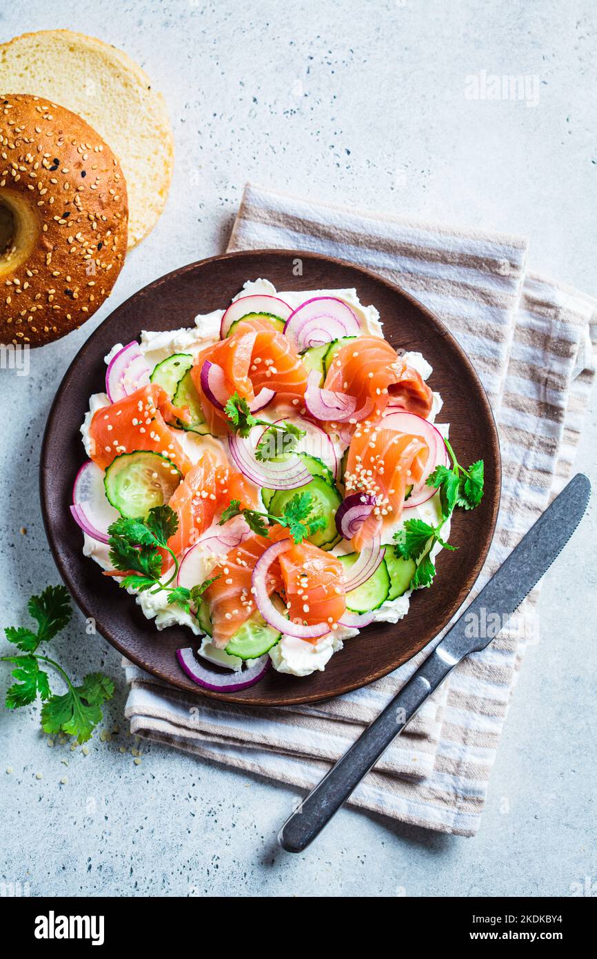 Butter board with salted salmon, cucumber, radish and cilantro on wooden plate for bagel, top