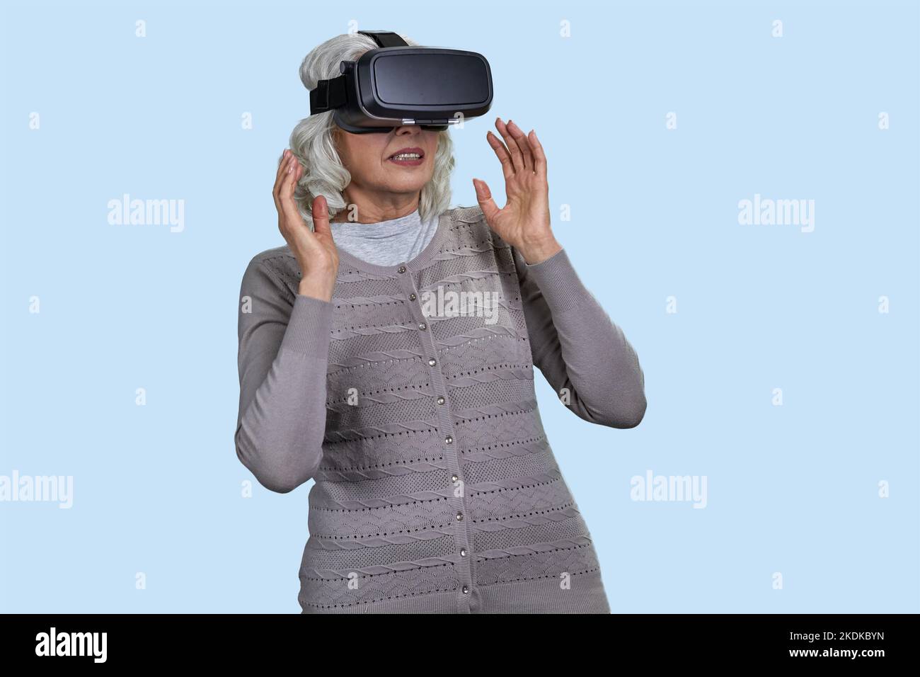 Senior woman with virtual reality headset on blue background. Old lady