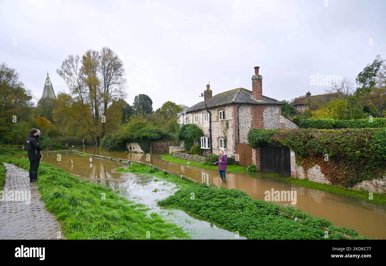 Alfriston East Sussex UK 7th November 2022 - A resident wades through floodwater from the Cuckmere River close to cottages in Alfriston village in East Sussex after more heavy rain which  is forecast to continue across Britain over the next few days : Credit Simon Dack / Alamy Live News Stock Photo