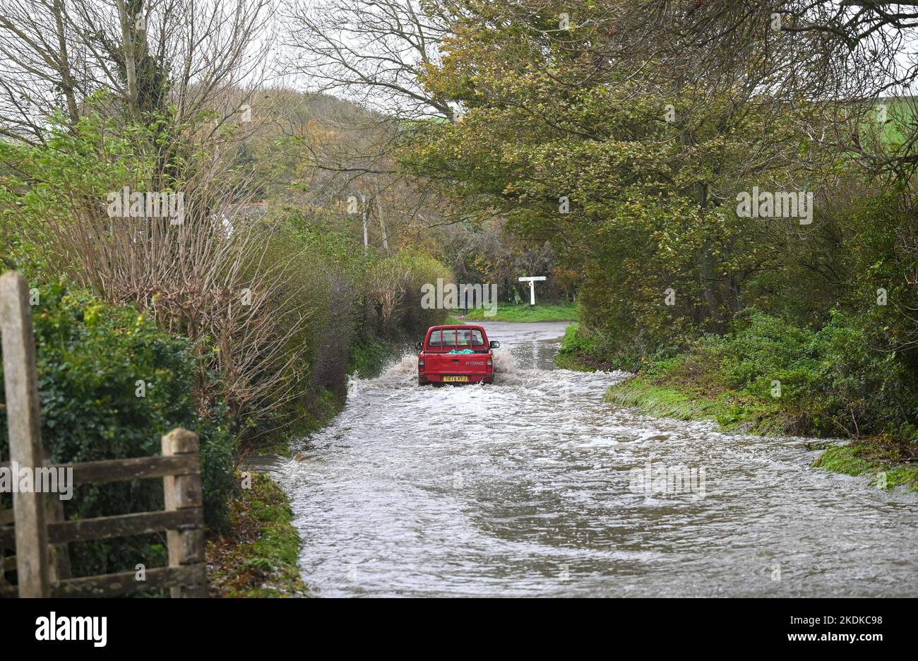 Alfriston East Sussex UK 7th November 2022 - A farm vehicle drives through a flooded lane in Alfriston village in East Sussex after more heavy rain which is forecast to continue across Britain over the next few days : Credit Simon Dack / Alamy Live News Stock Photo