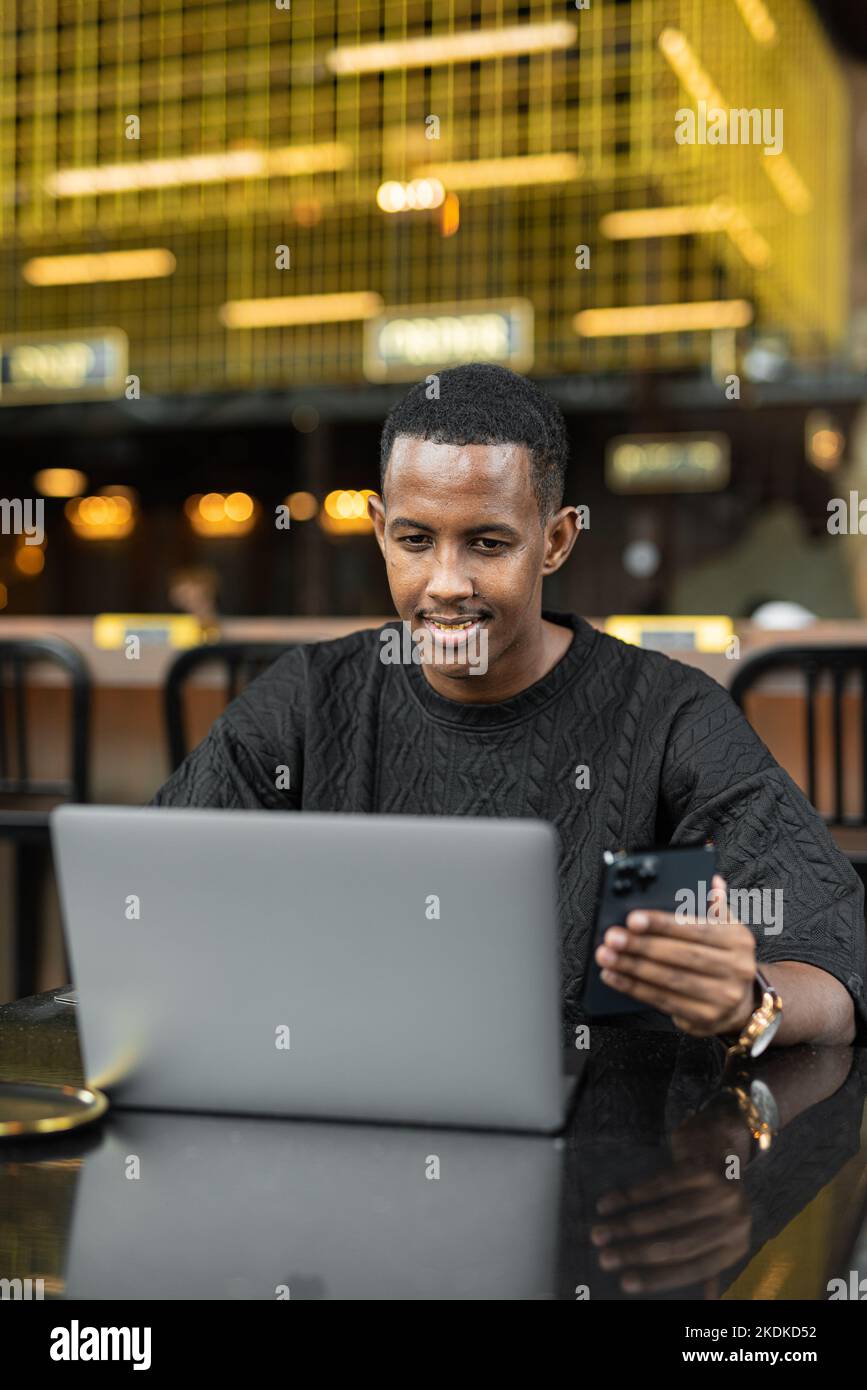 Portrait of handsome young black man using laptop computer in coffee shop Stock Photo