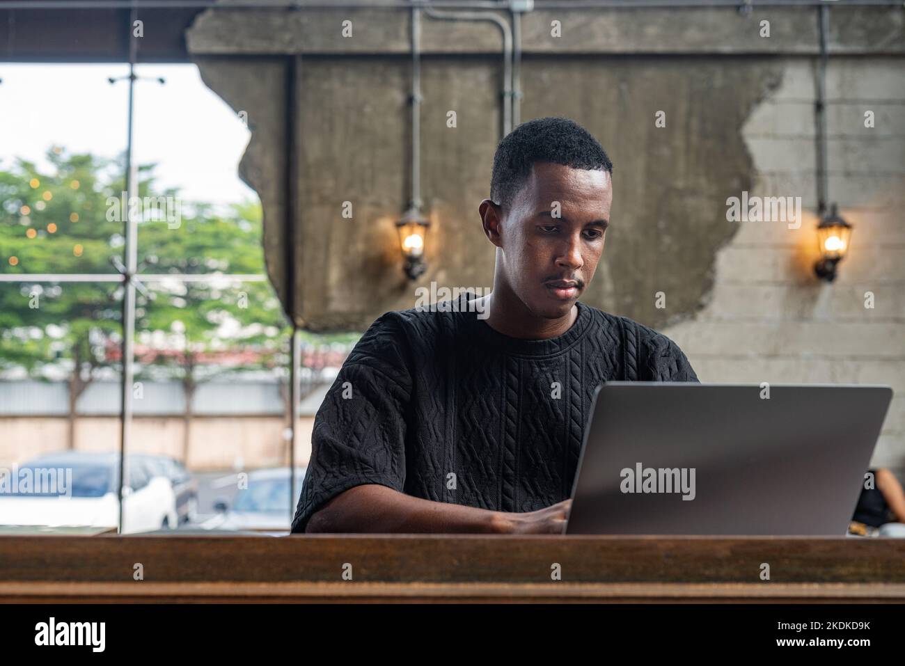 Portrait of handsome black man sitting and using laptop computer indoors Stock Photo