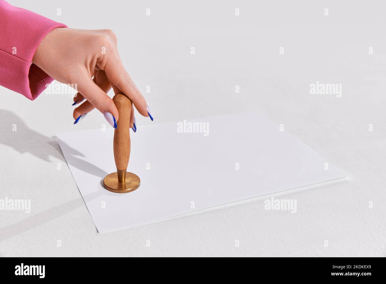 Female hand putting stamp on paper document symbolizing permission over