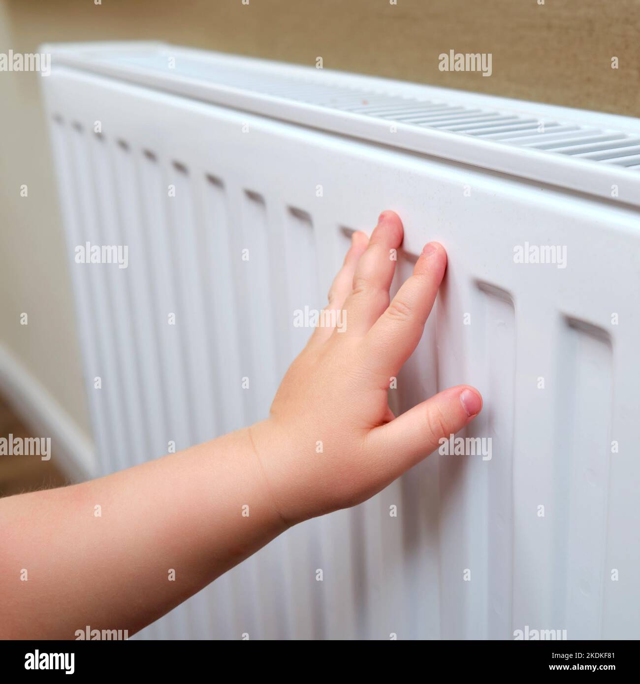 Toddler baby holding on to the radiator, child hand on the heating
