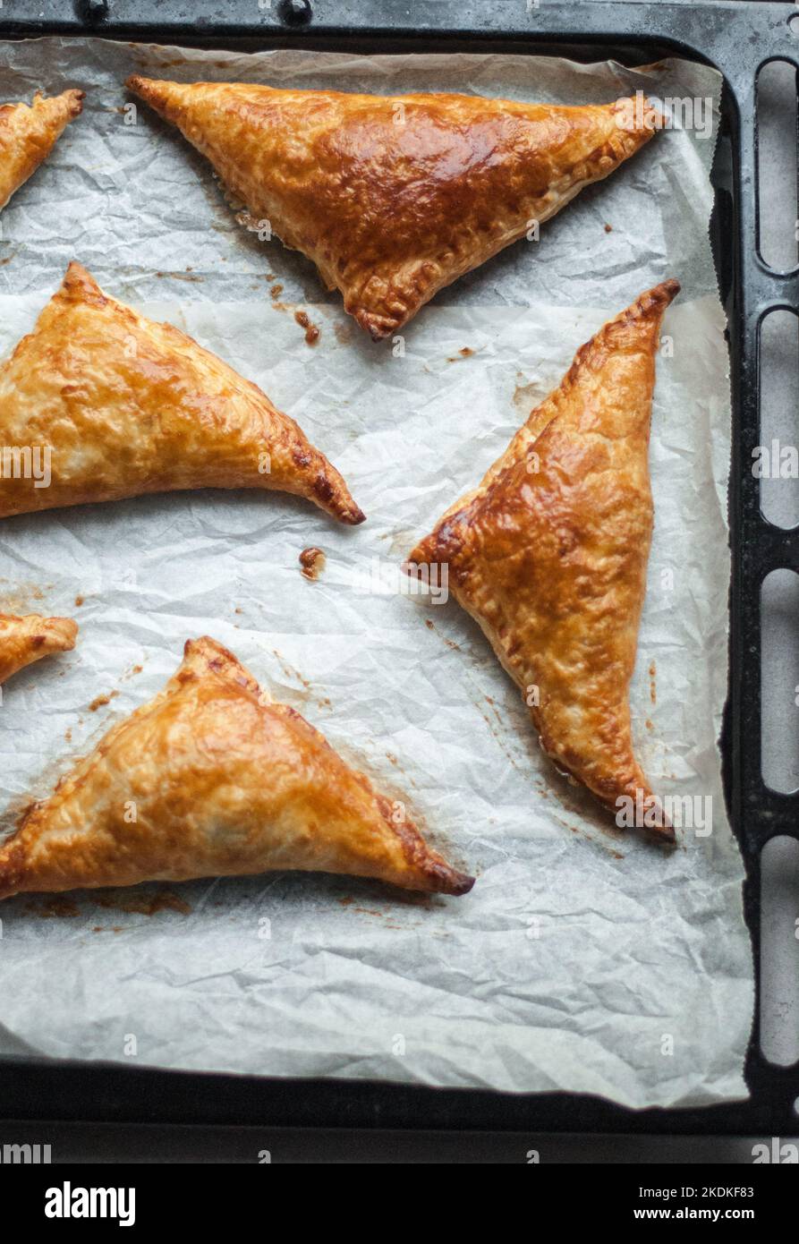 Baked pies in the form of triangles from puff pastry, on a baking paper