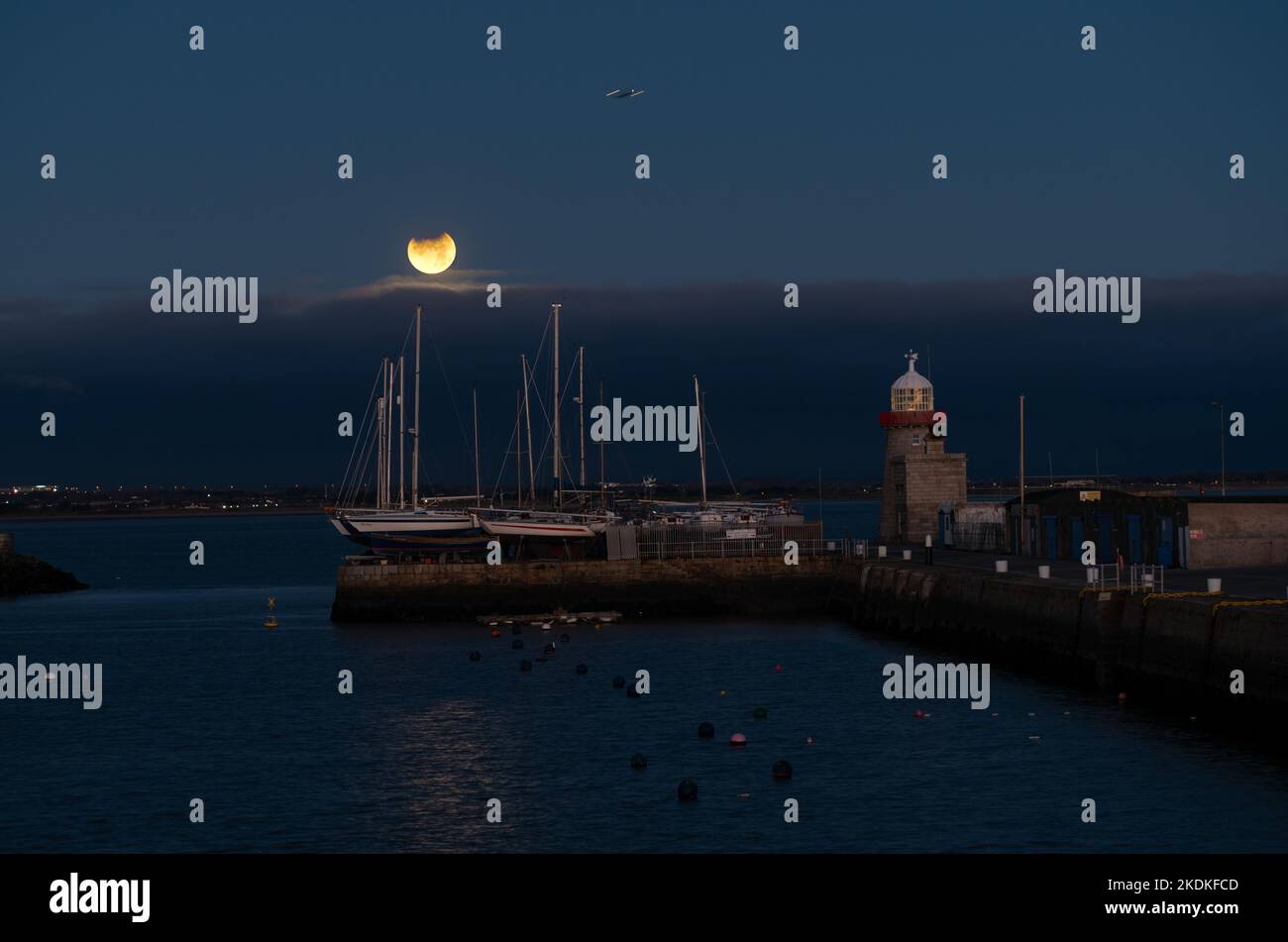 The November 2021 partial lunar eclipse setting at Howth Harbour. Stock Photo
