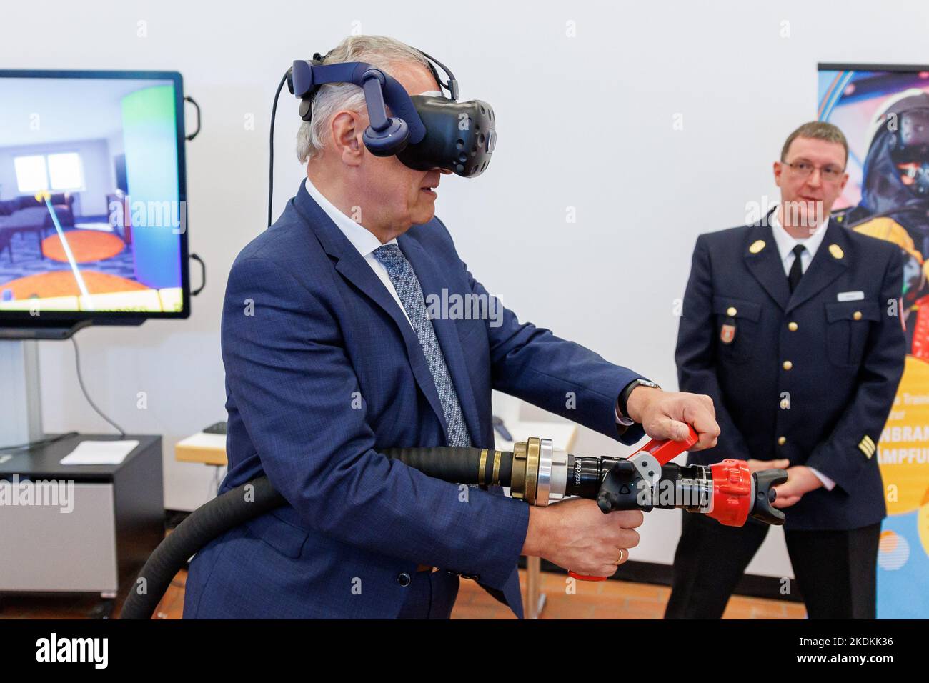 Wurzburg, Germany. 07 November 2022, Bavaria, Würzburg: Joachim Herrmann (l, CSU), Bavaria's Minister of the Interior, tries out virtual training for indoor firefighting at the Würzburg State Firefighting School, wearing VR goggles and using a hollow jet pipe with VR technology. Credit: dpa picture alliance/Alamy Live News Stock Photo