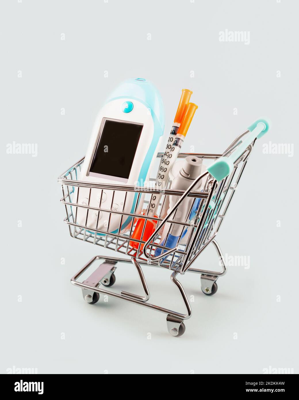 Diabetes card with glucose meter, test strips for determining blood sugar levels, syringes for insulin injections in shopping trolley on blue backgrou Stock Photo