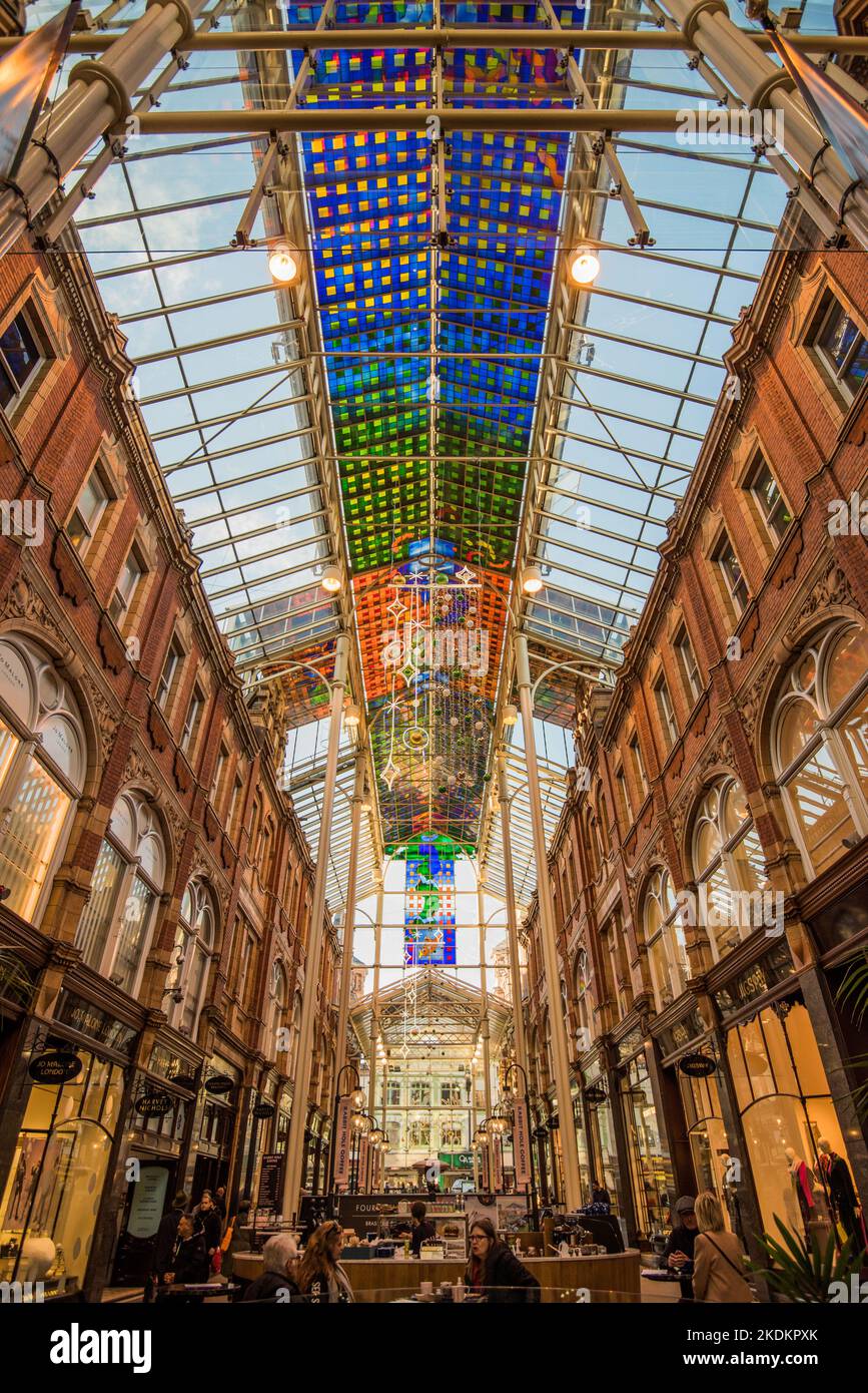 Victoria Quarter, one of the famous Leeds arcades having a brightly coloured, modern, abstract pattern,  stained glass canopy in blue, yellow & red. Stock Photo