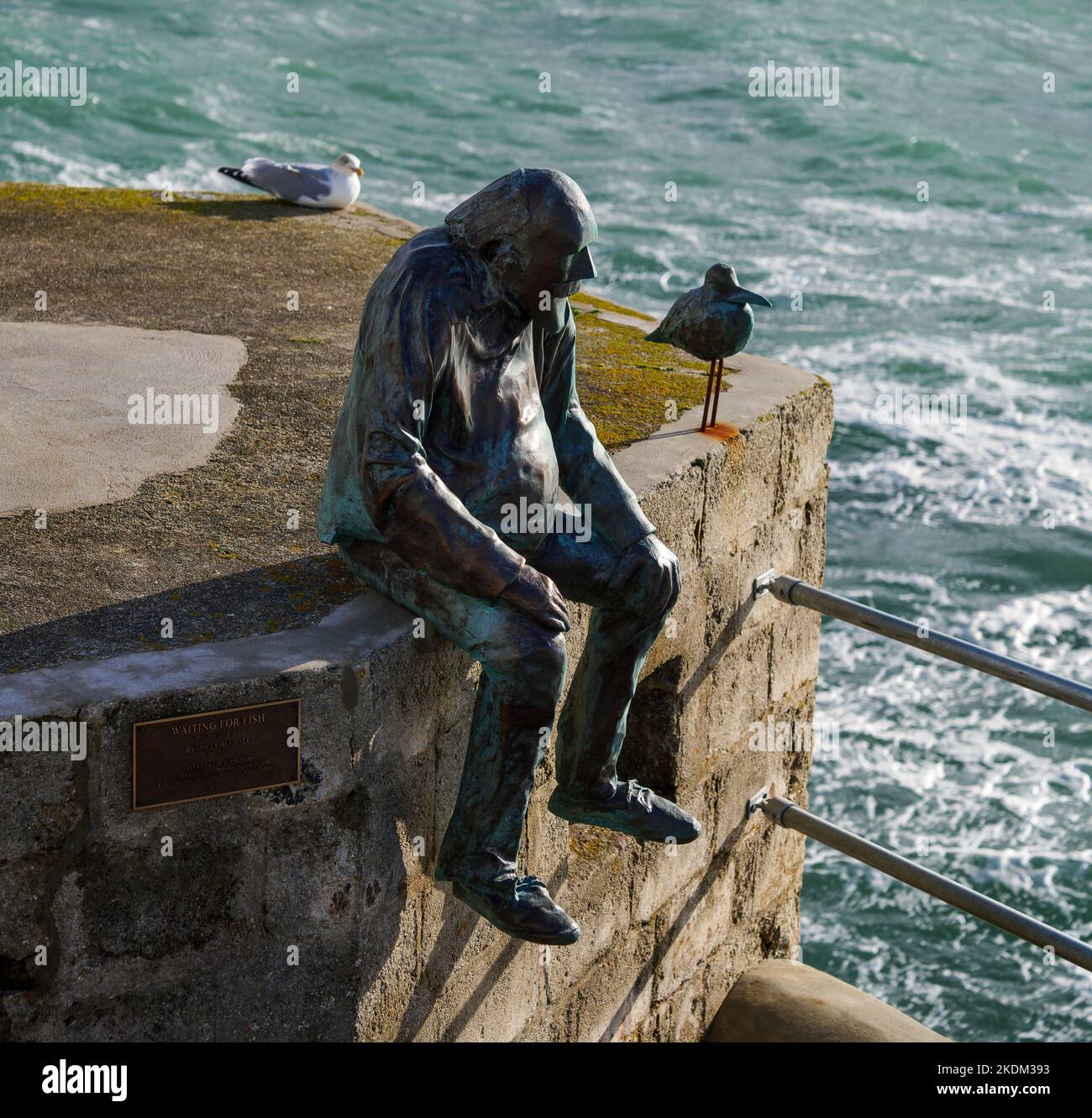 New fisherman statue and sea gul on Porthleven harbour.  With a real sea gul watching over them in the background. Stock Photo