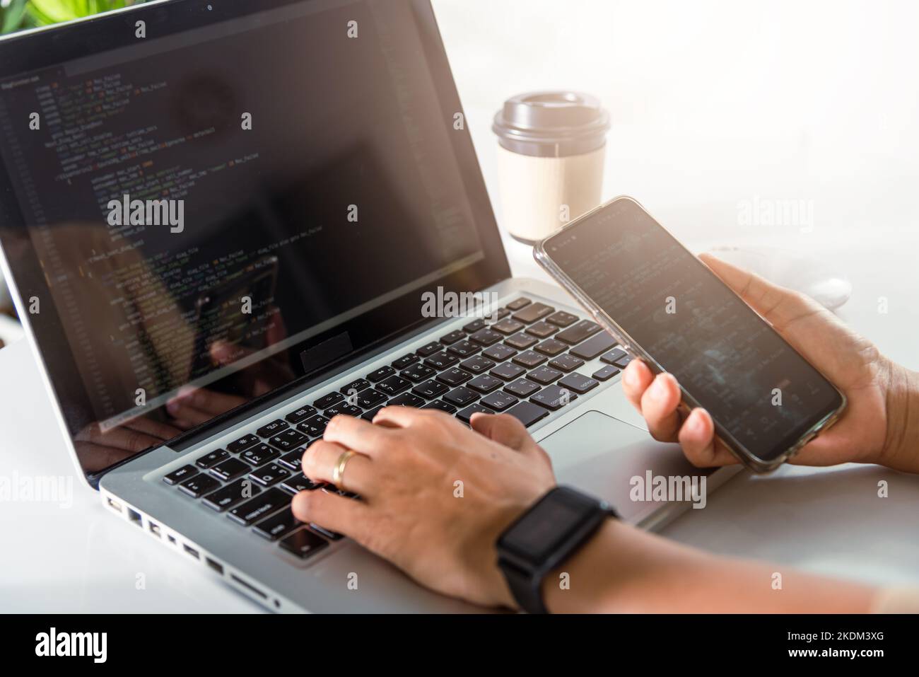 Programmer woman looking mobile phone program code at workplace Stock Photo