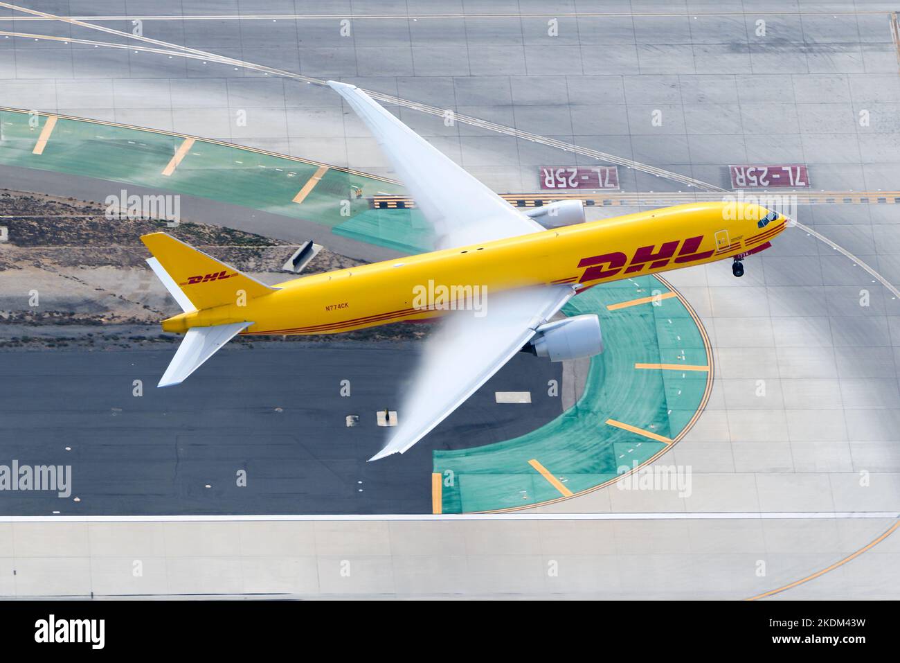 DHL Cargo aircraft Boeing 777 taking off. Transport of freighter on DHL Kalitta Air airplane 777F. Plane take off with condensation above wings. Stock Photo