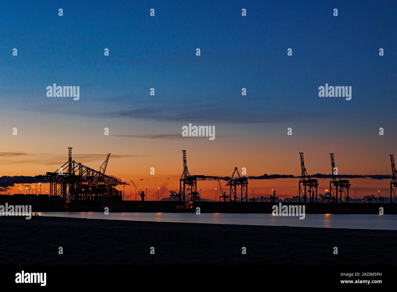 Panoramic image of the cargo port at sunset. Gdansk at night with container terminals, cargo cranes at sea and clear blue sky. Cargo sea port Stock Photo
